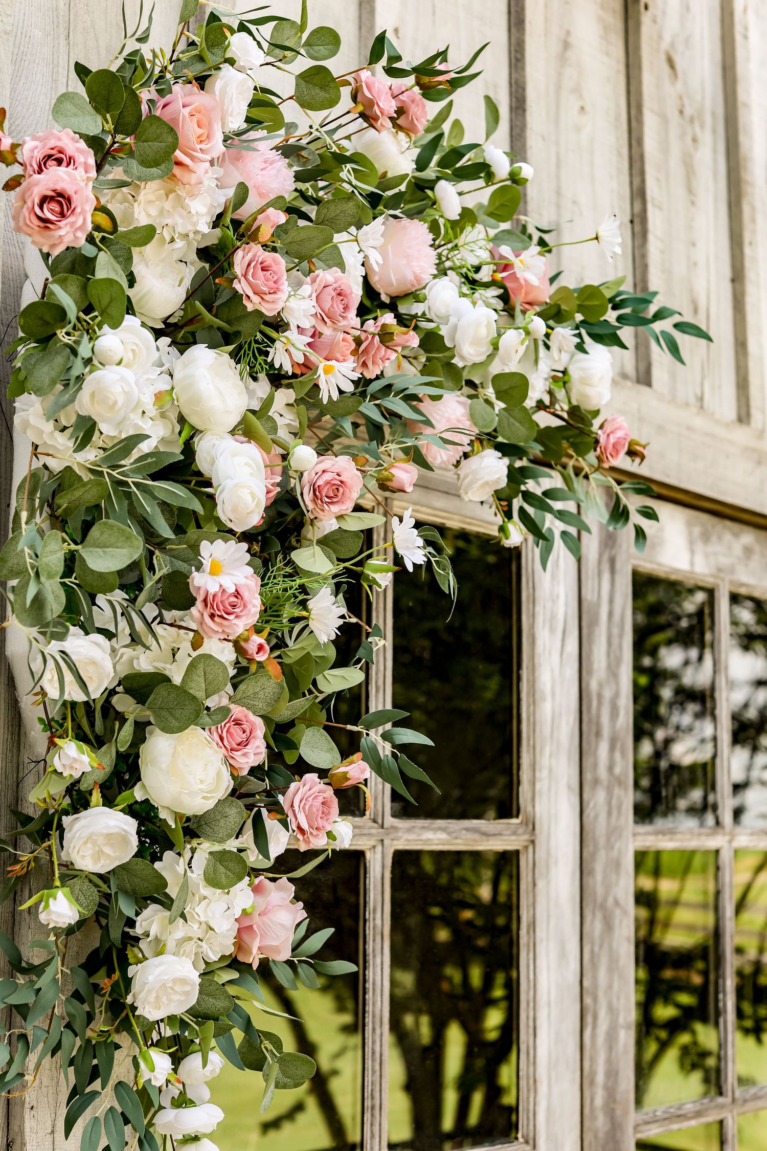 Romantic floral arch with pink and white roses decorating a vintage window frame.