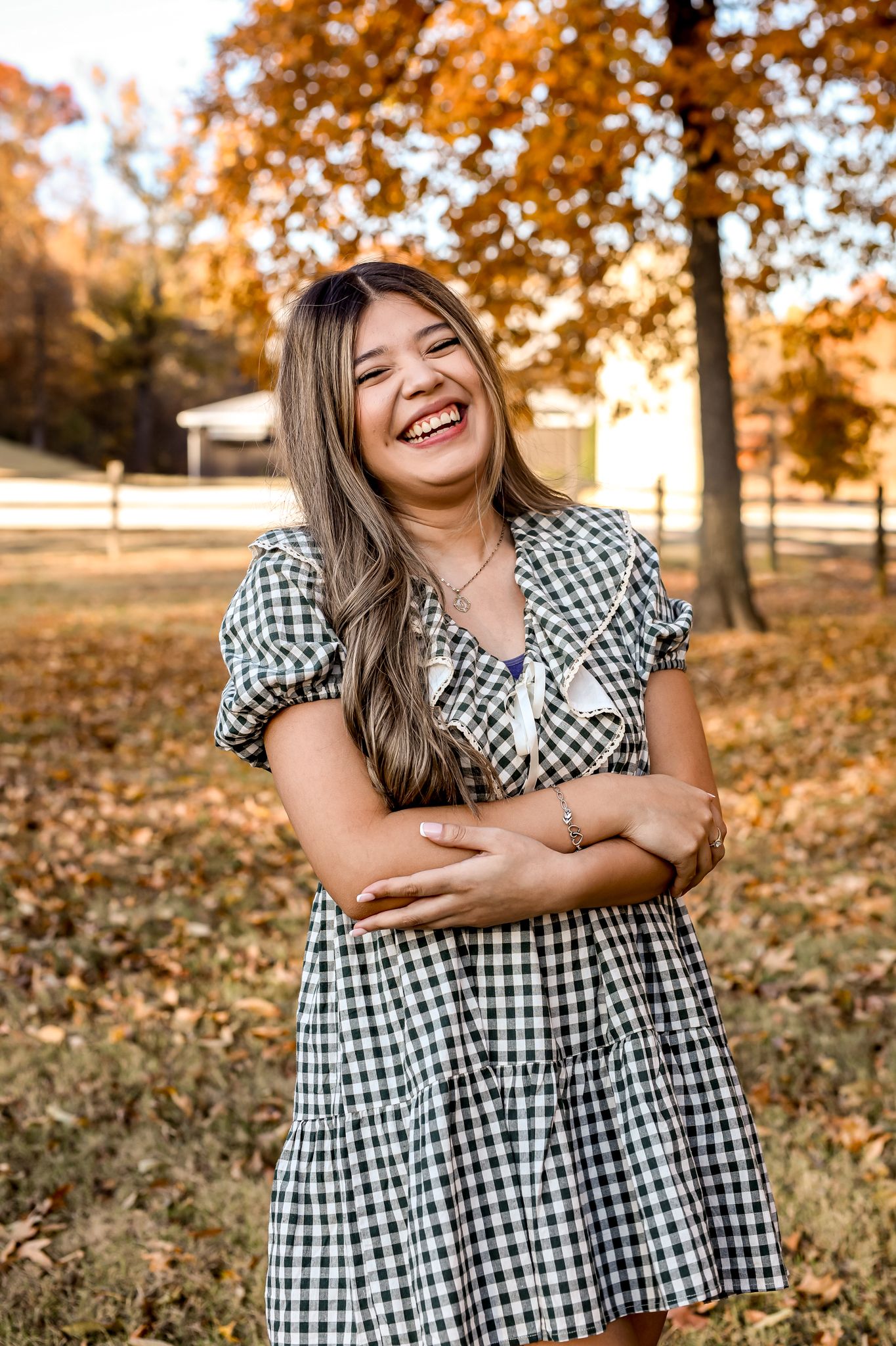 Cheerful portrait session in autumn setting wearing black and white gingham dress.