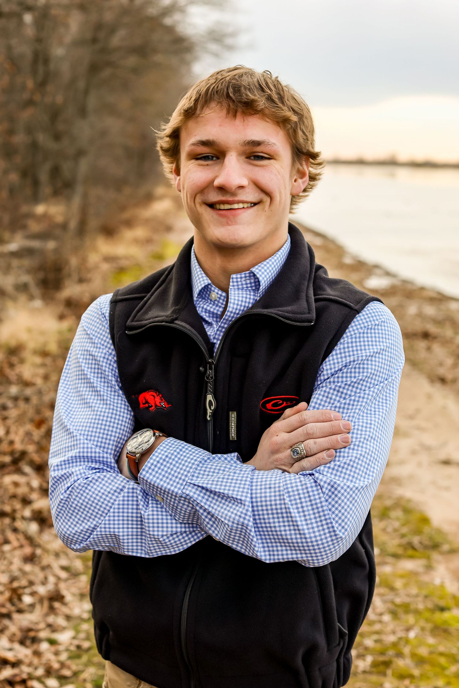 Person wearing a blue checkered shirt and black vest poses outdoors in a series of casual portraits.