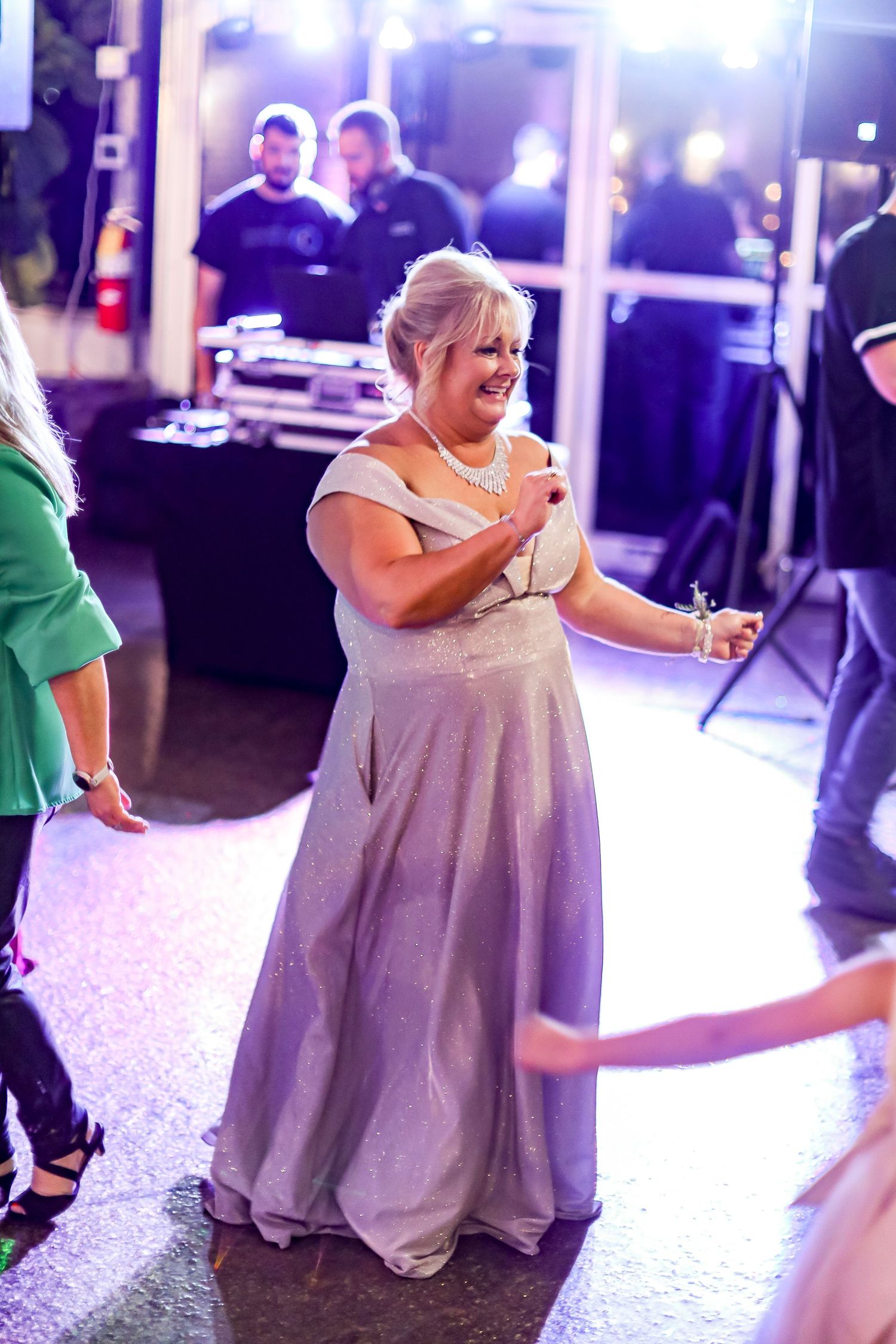 Woman in a flowing gray gown dances joyfully at an evening celebration.
