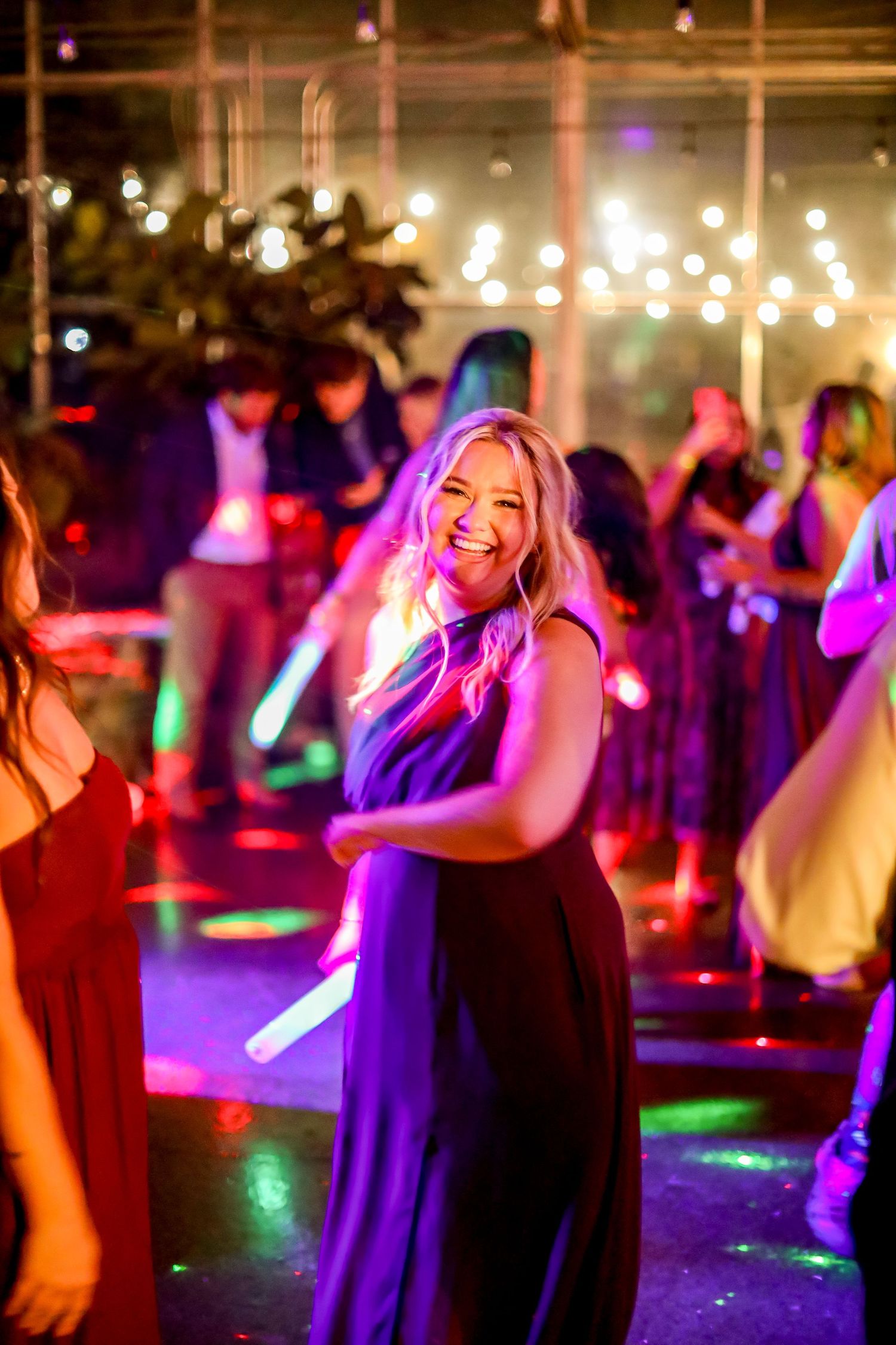 People dancing under colorful lights at a nighttime celebration event.