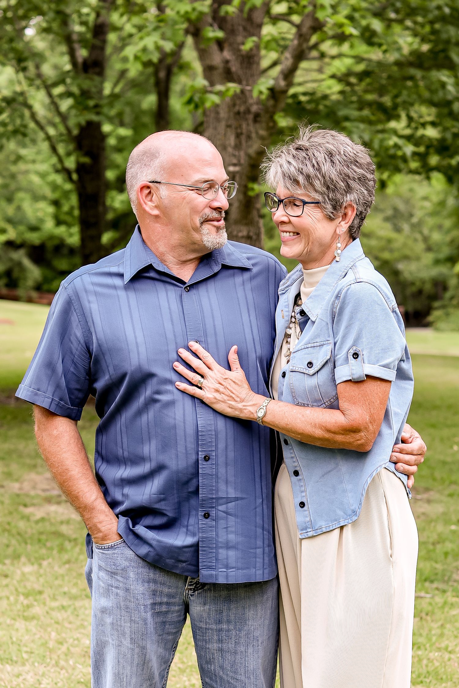 Mature couple shares loving moment while posing outdoors in casual attire.