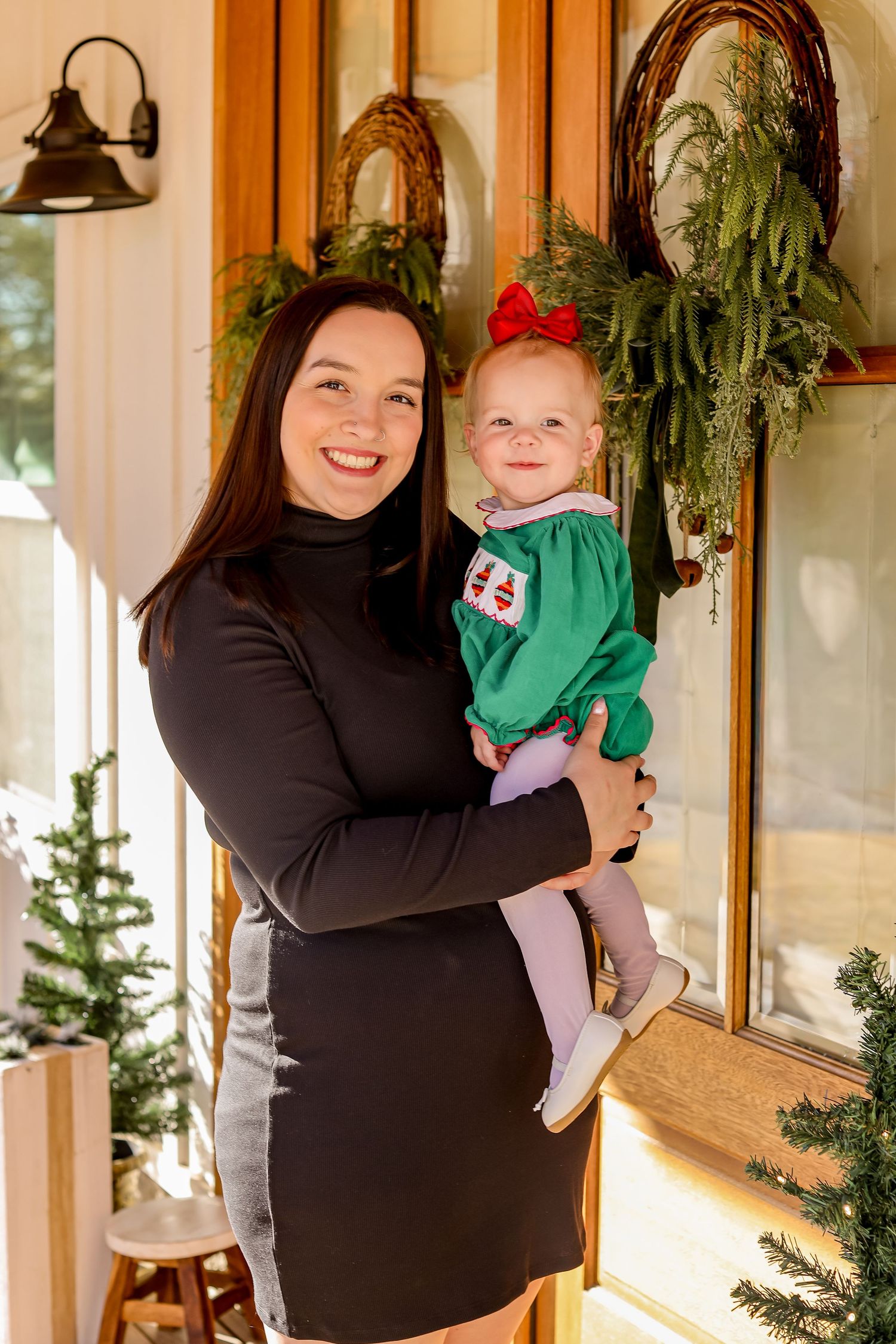 Holiday portrait on a decorated front porch with festive greenery and Christmas decorations.