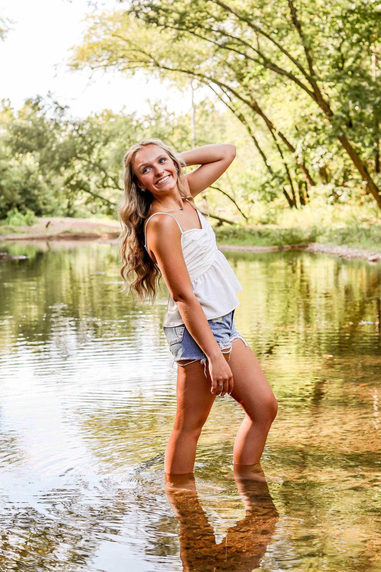 Summer lifestyle photos of someone playing in shallow creek water with golden sunlight.