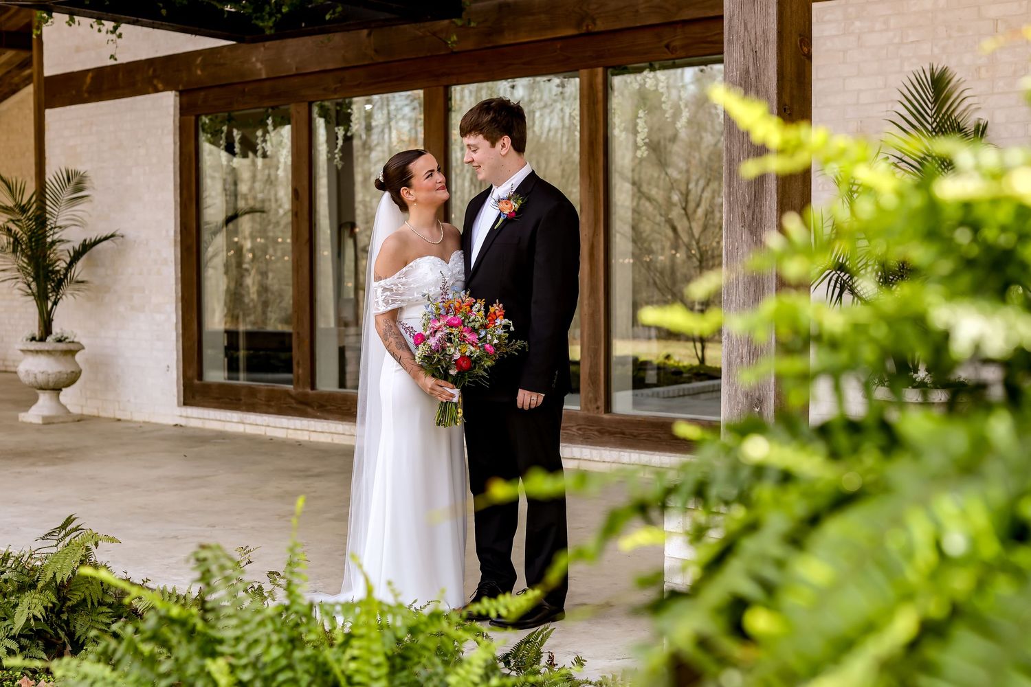 Romantic wedding portraits captured in a covered outdoor walkway with natural greenery.