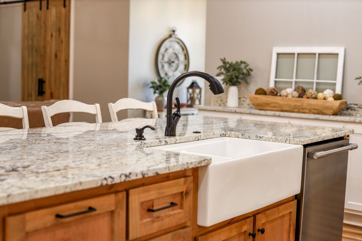 Farmhouse style kitchen with white cabinets, granite countertops and rustic wood accents.