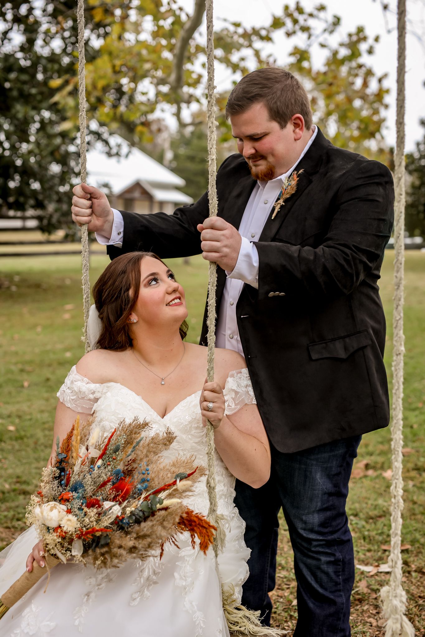 Wedding couple shares a playful moment on a rope swing in an outdoor garden setting.