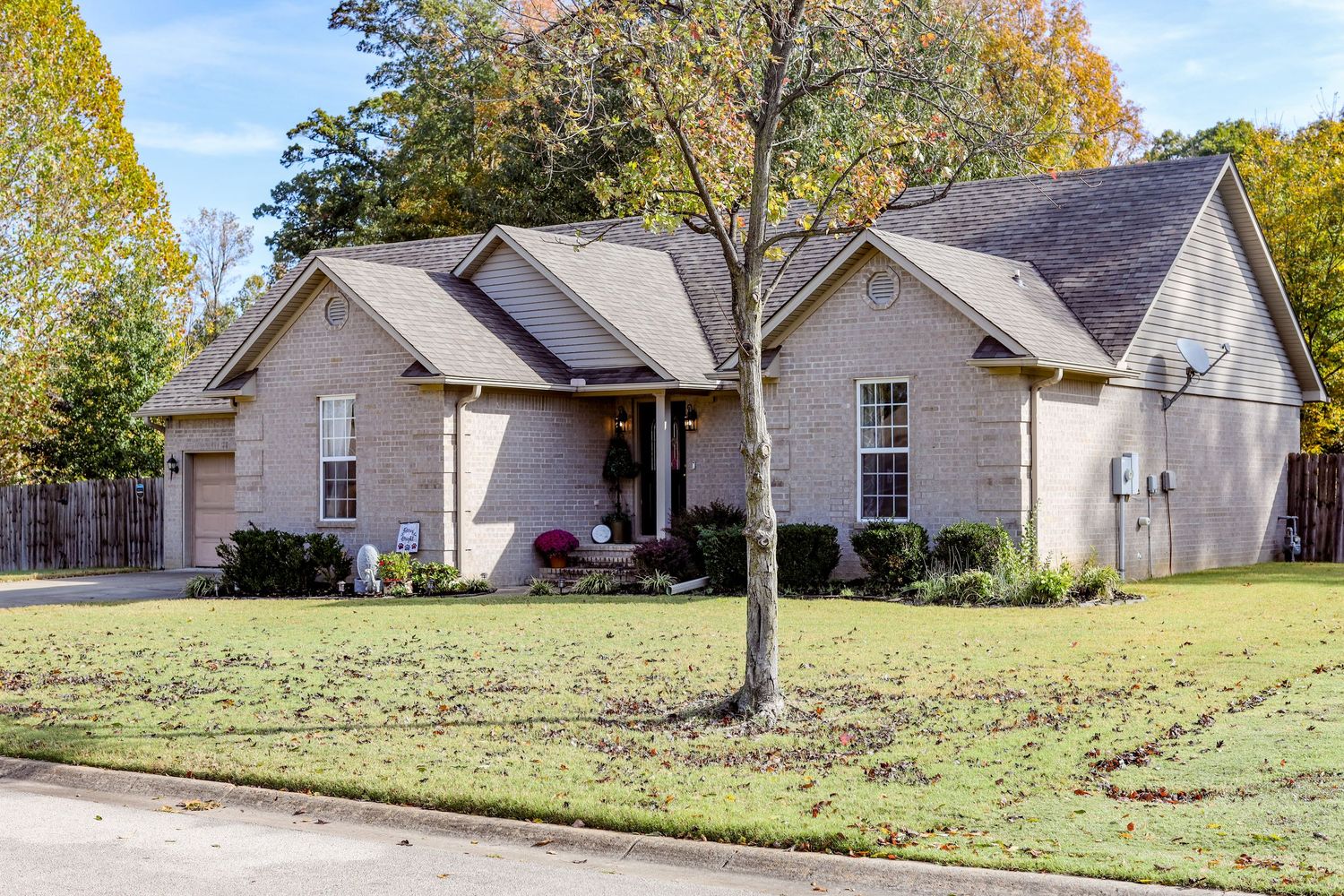 Street view of residential neighborhood with single-story homes and mature trees.