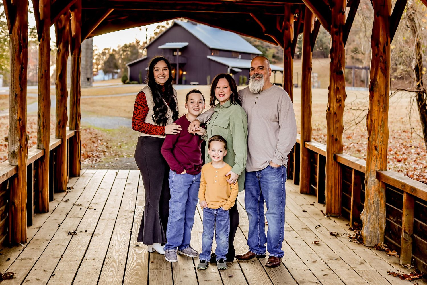 Family portrait on a wooden covered bridge during autumn season.