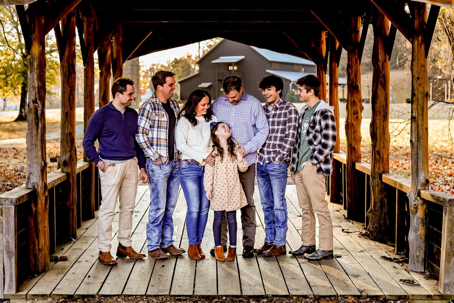 Group portrait on covered wooden bridge with rustic backdrop.