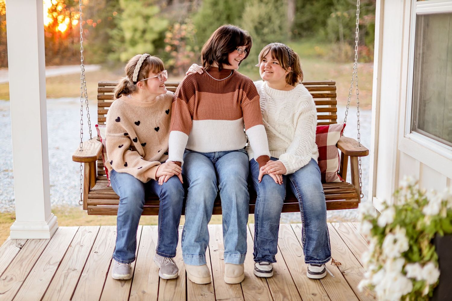 Group sitting together on wooden porch bench during golden hour sunset.