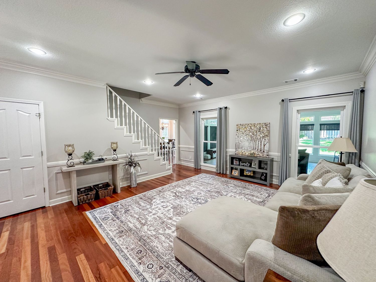 Modern living room interior with hardwood floors, white walls, and plush furniture.