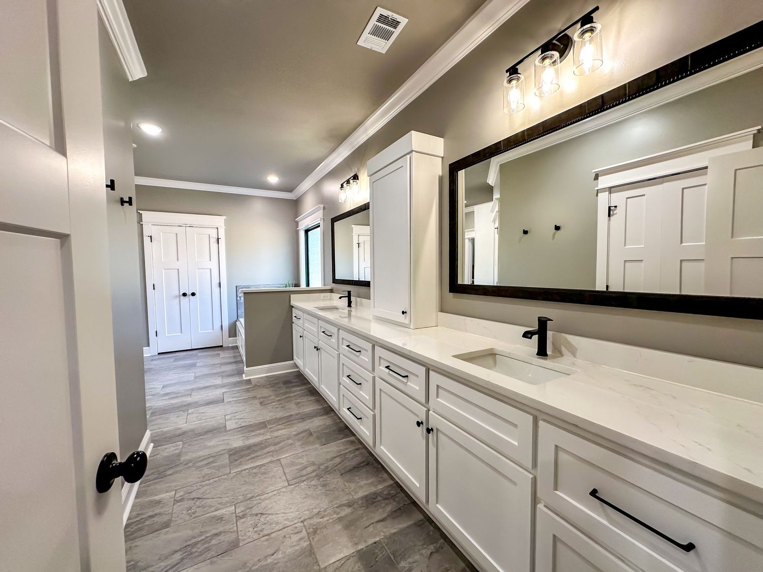 Long hallway with gray flooring and white trim featuring modern black door hardware.