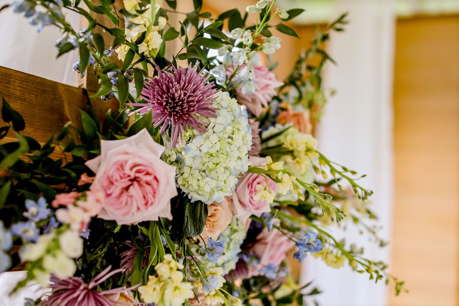 Elegant floral arrangement with pink roses and purple chrysanthemums against light background.