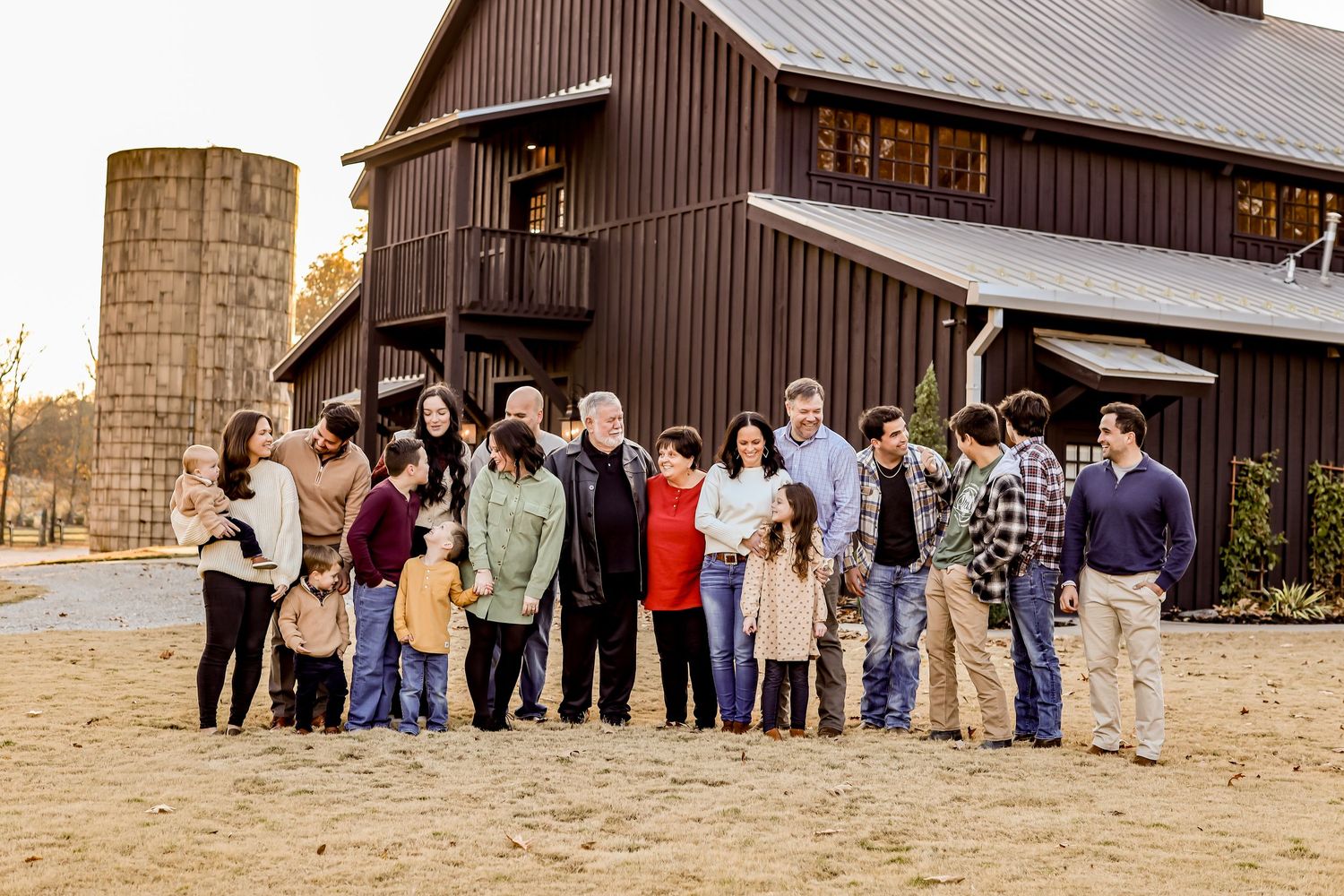 Large group portrait in front of a rustic brown barn with silo.