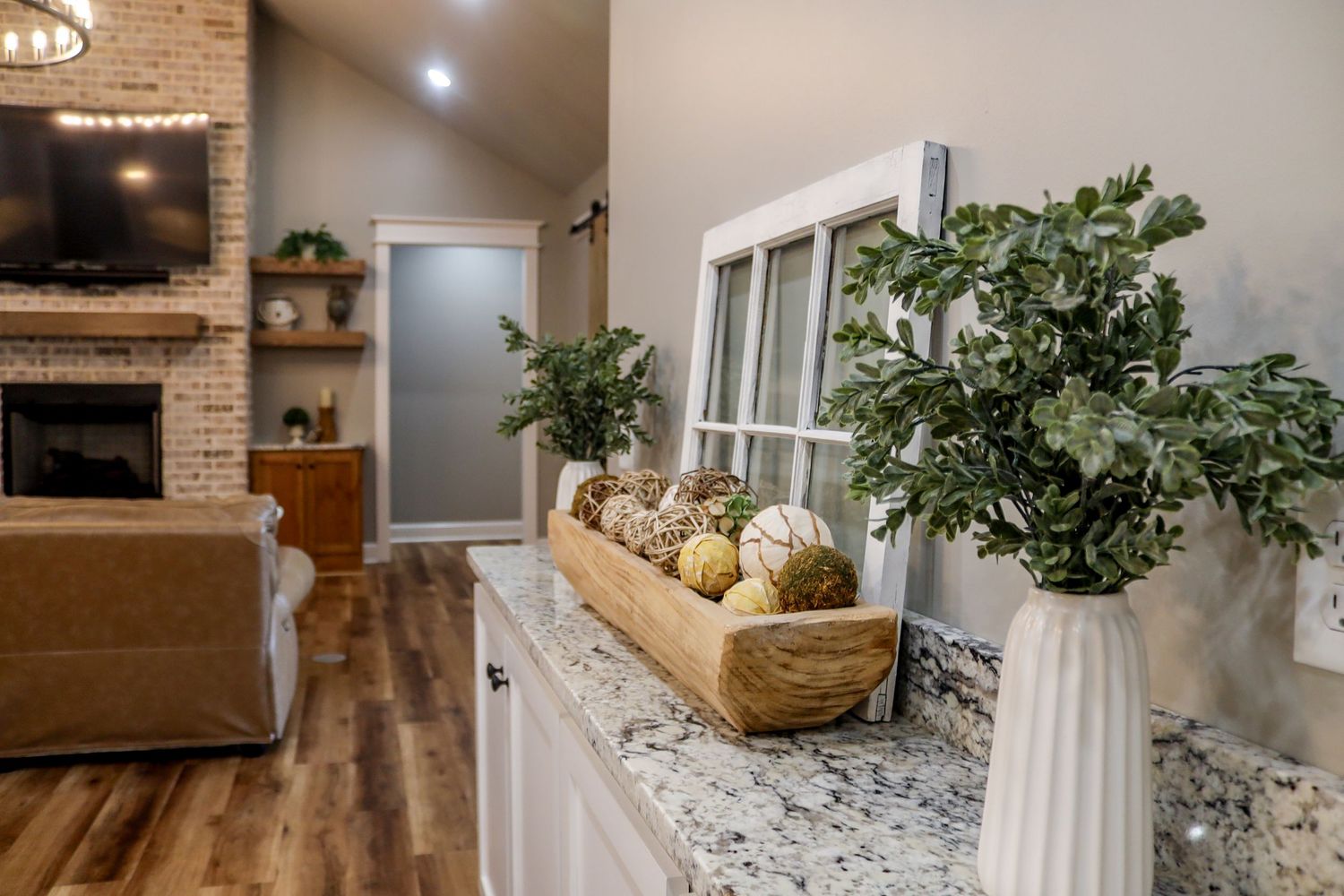 Bright modern kitchen featuring granite countertops and decorative greenery.
