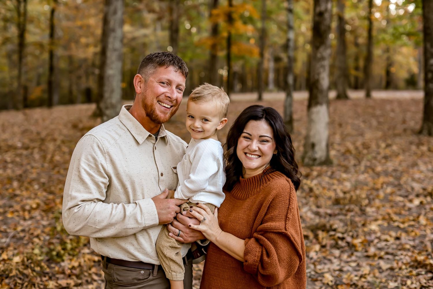Candid autumn family moments captured among fall foliage in wooded setting.