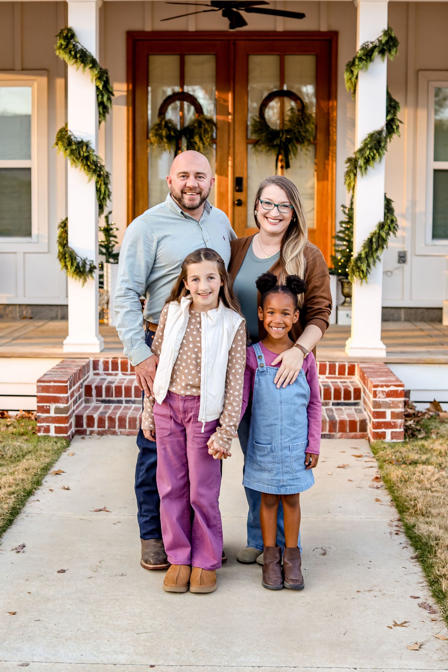 Casual family portrait on front porch steps with decorative holiday garland visible in background.