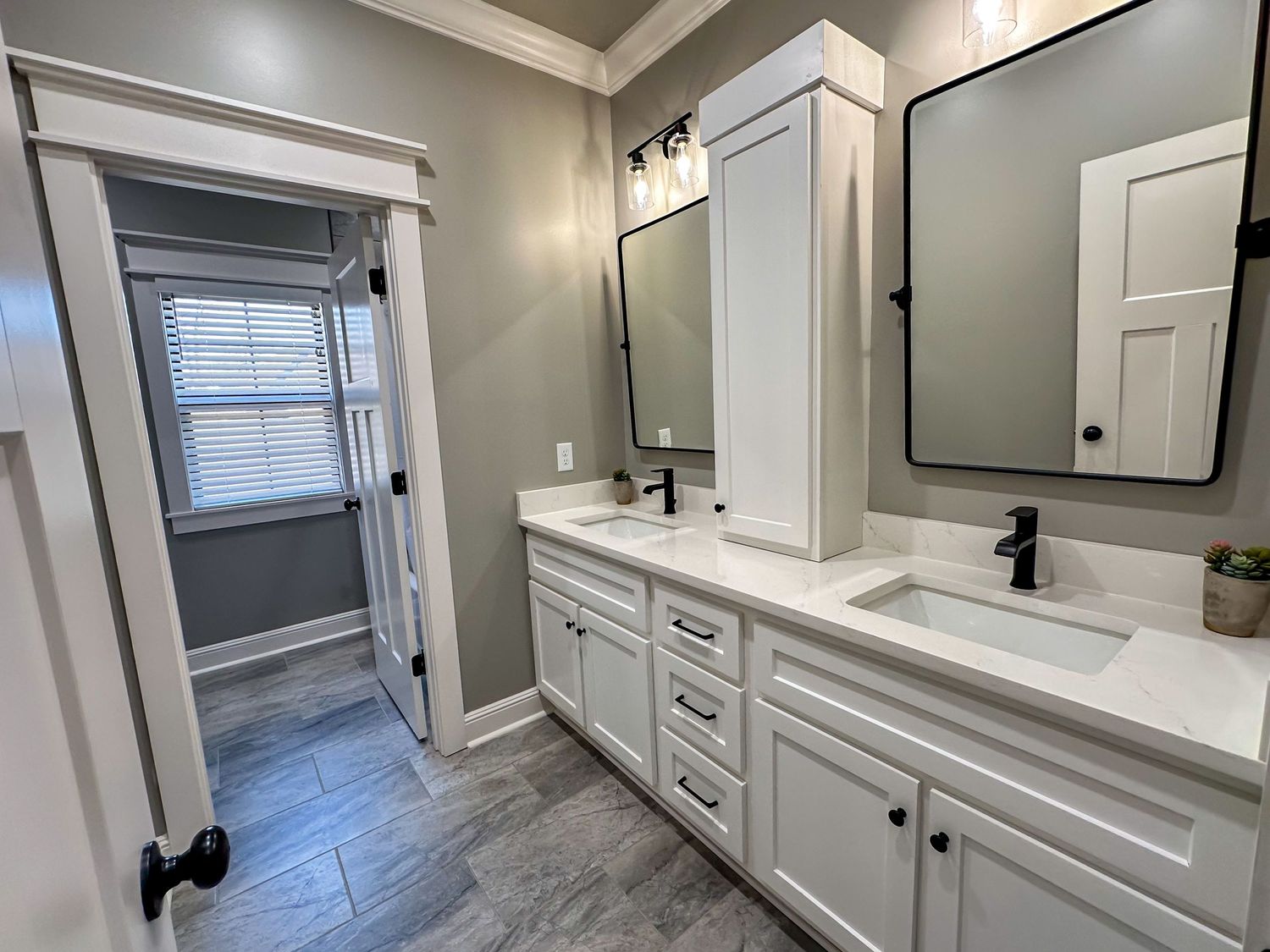 Modern bathroom with gray tile flooring and white cabinetry featuring clean lines.