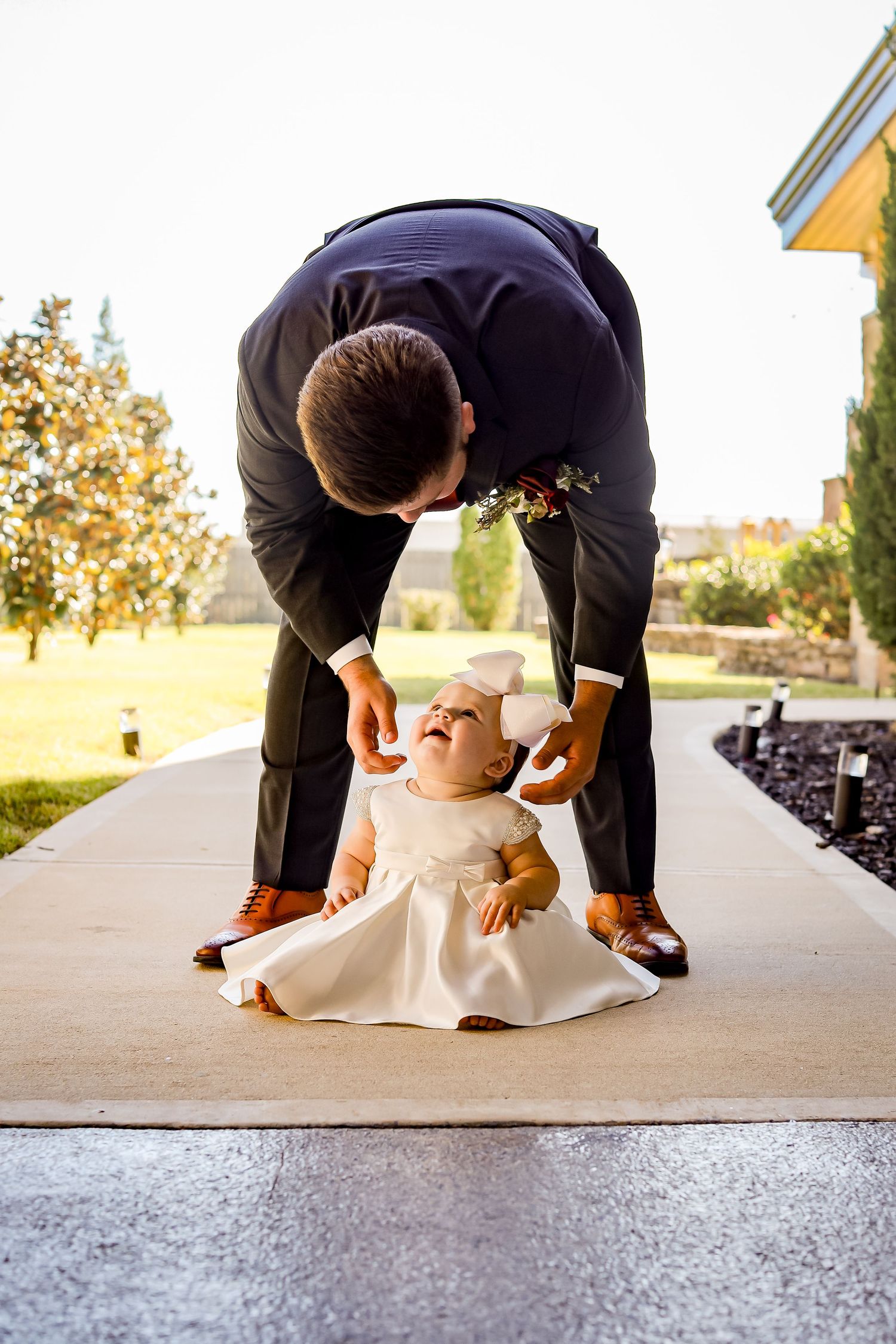 Sweet moment captured on a sidewalk with formal attire and a small white dress.