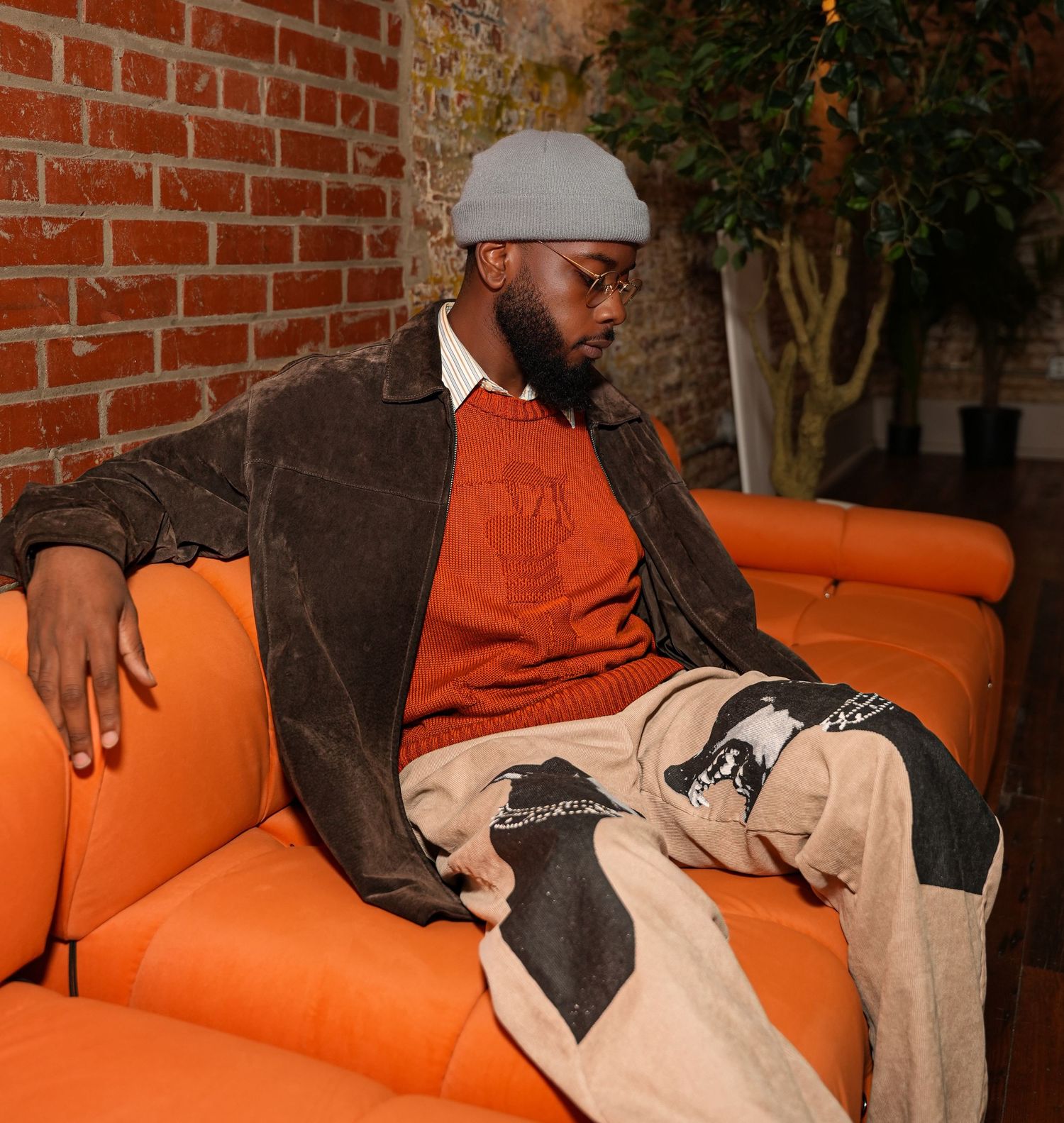 Casual portrait series on orange couch with relaxed poses.