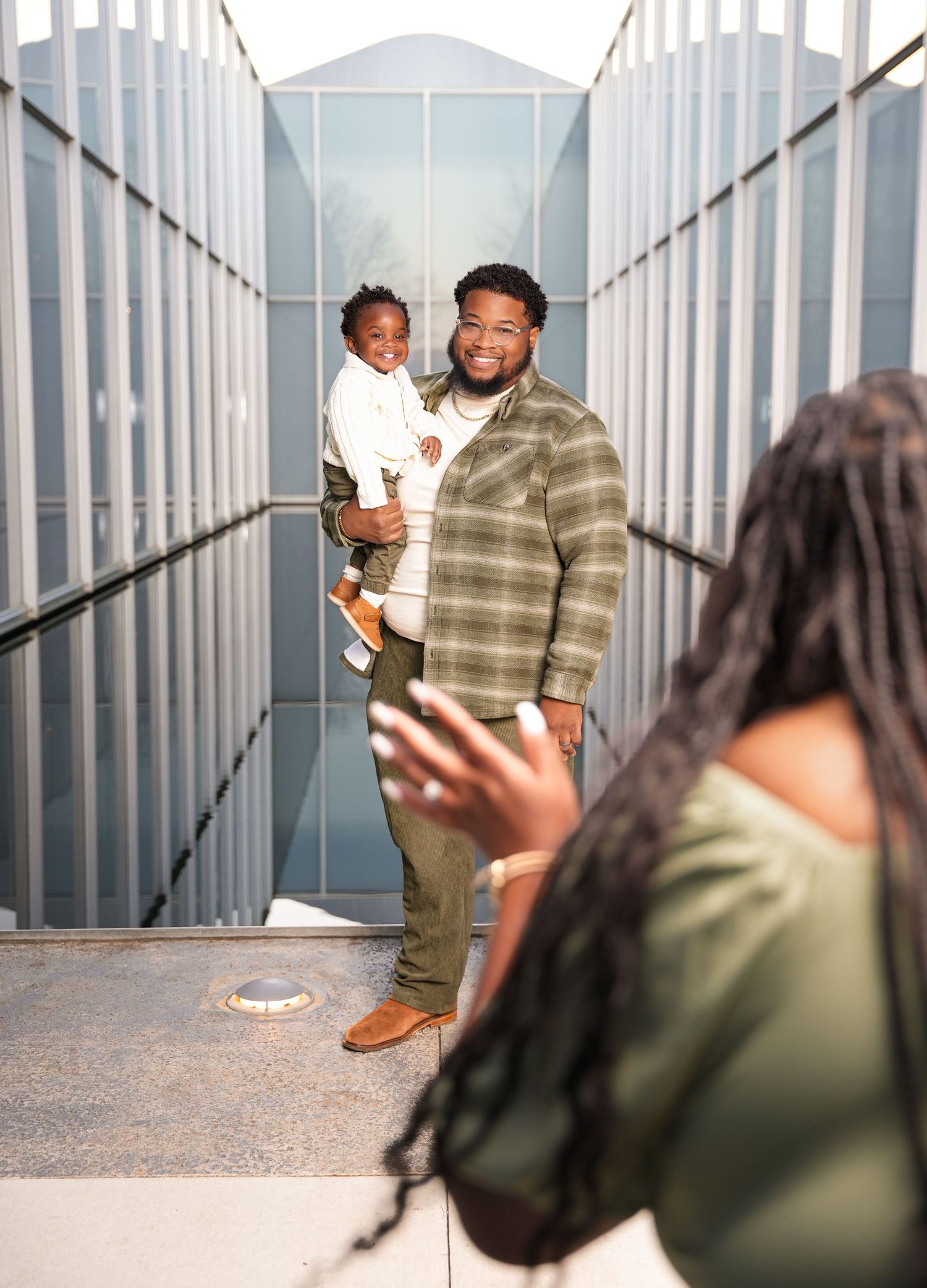 Creative engagement session with architectural elements and modern glass windows.