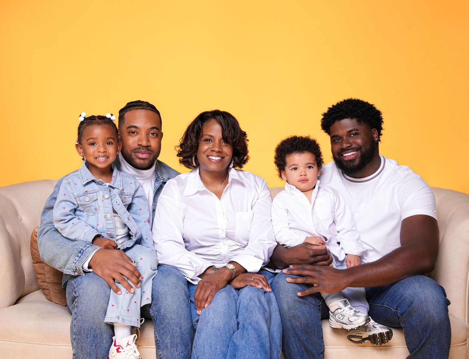 A family wearing coordinated light blue and white outfits poses together against an orange background.