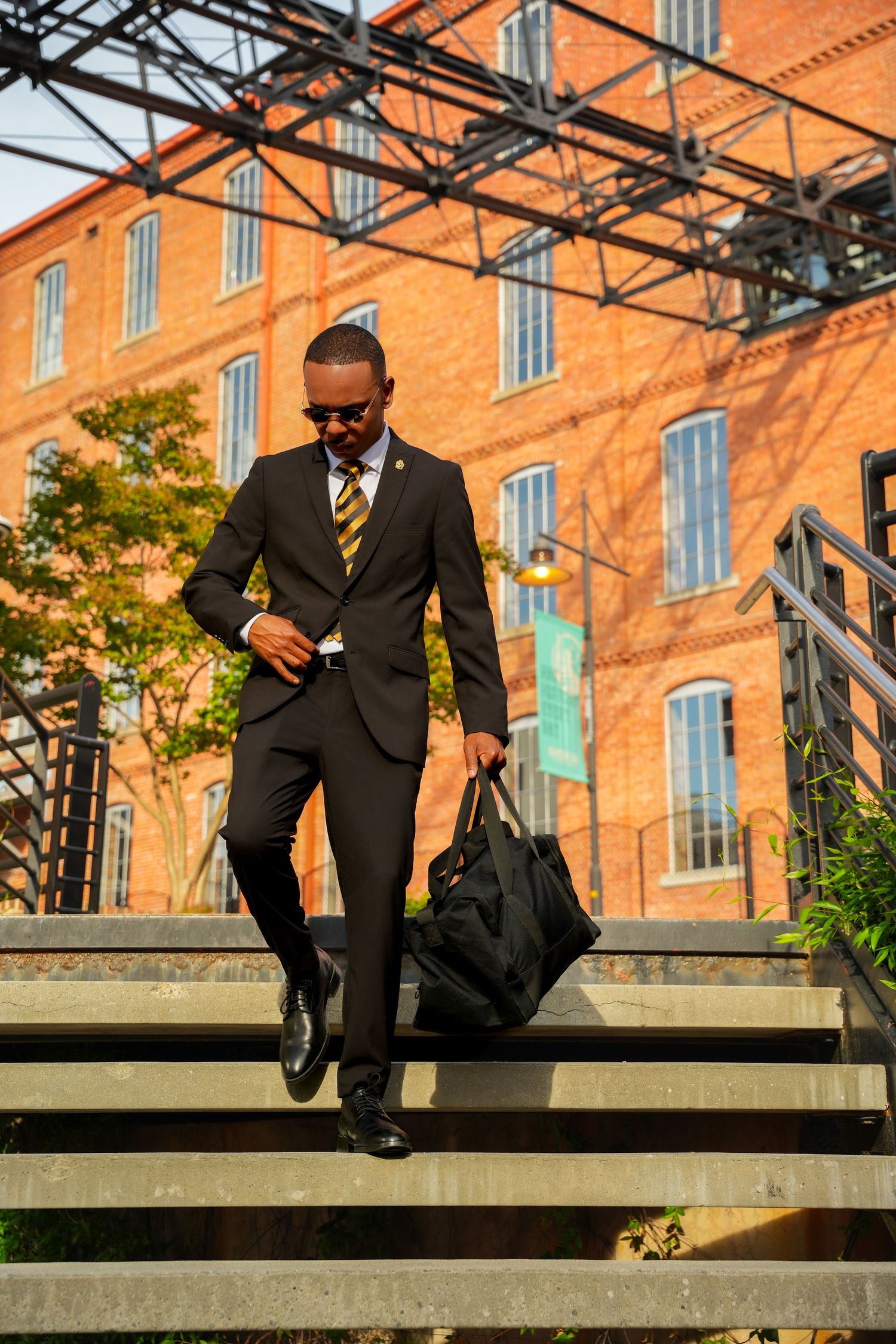 Professional in suit walks along brick building exterior during golden hour.