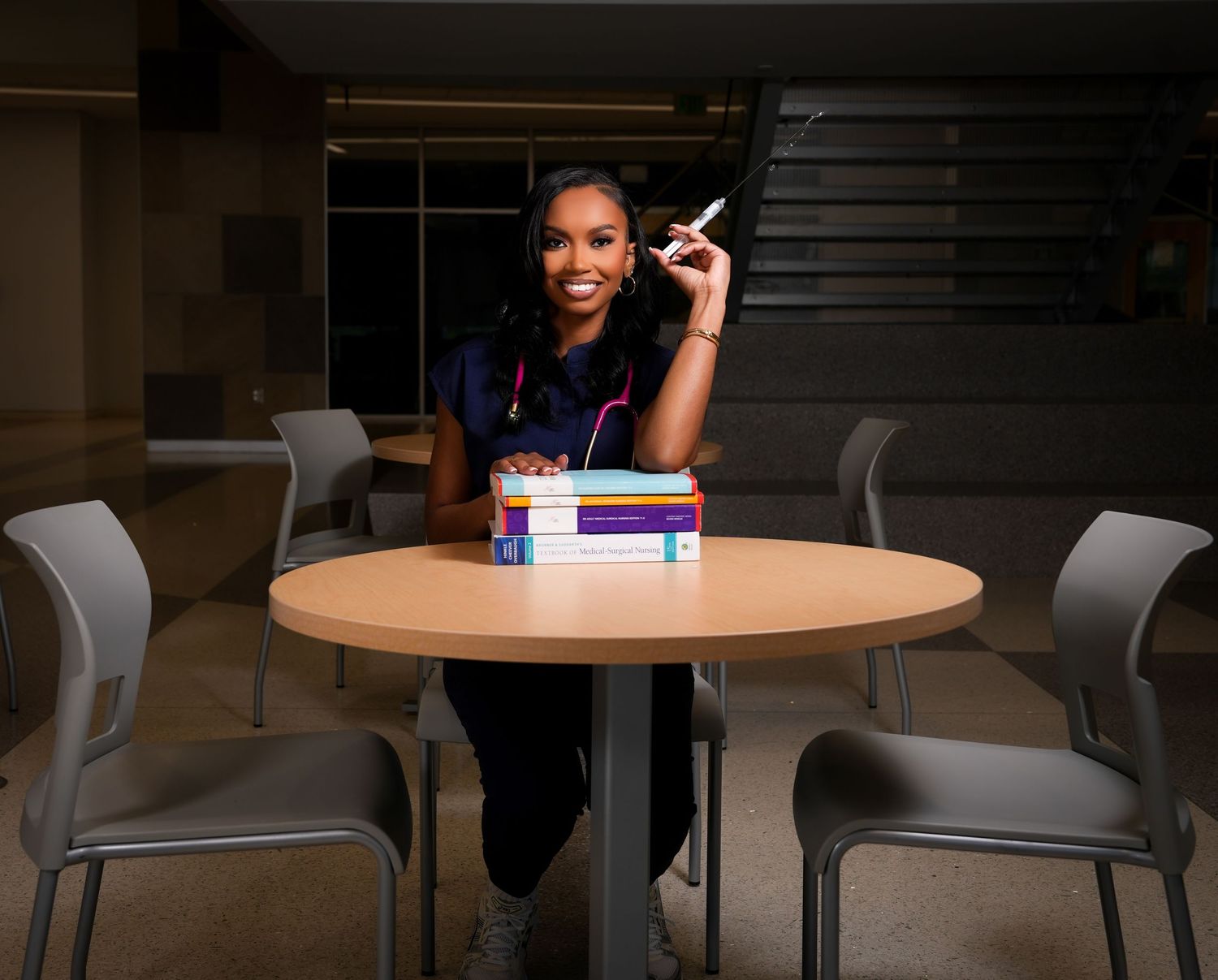 Student studying with textbooks at a round table in a modern library setting.