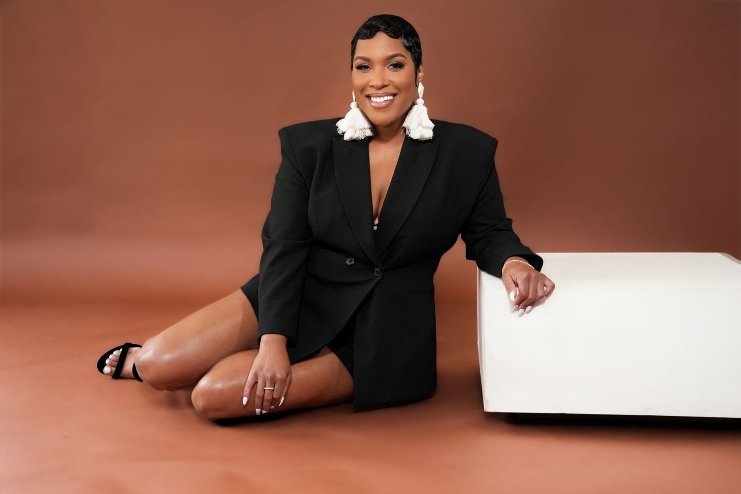 Professional studio portrait session with black outfit against brown backdrop.