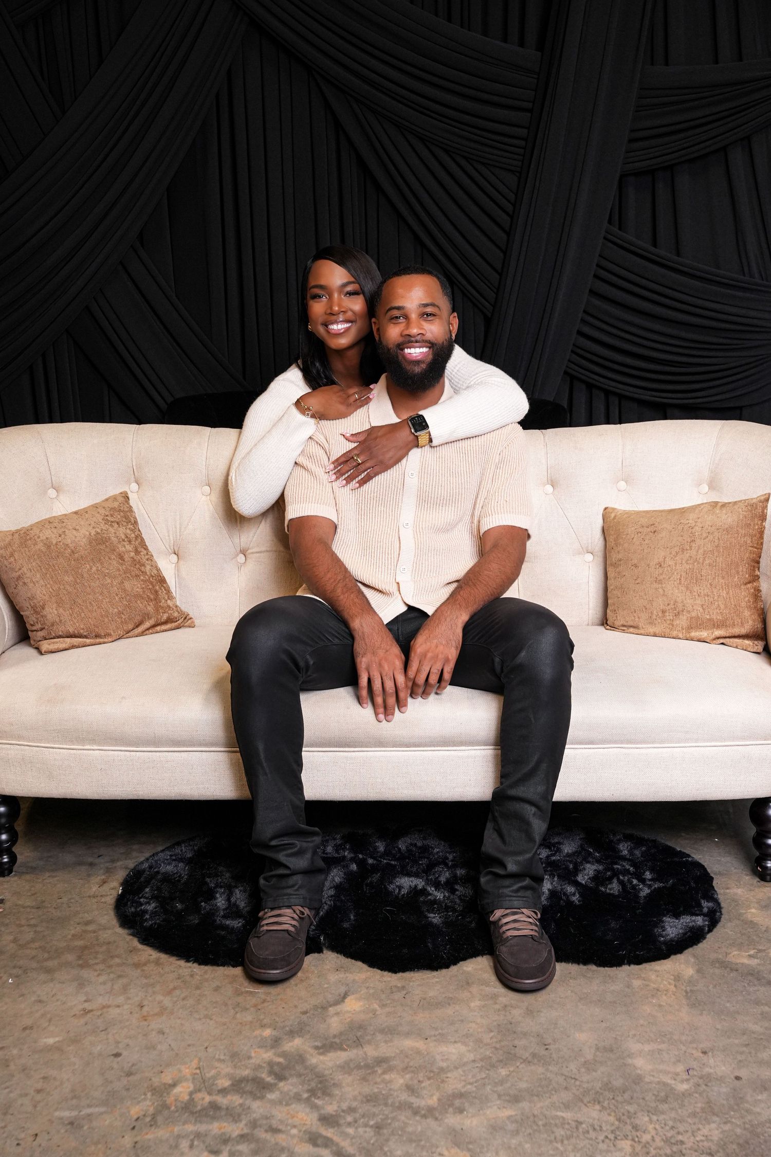 Couple's portrait session on white couch with decorative throw pillows.