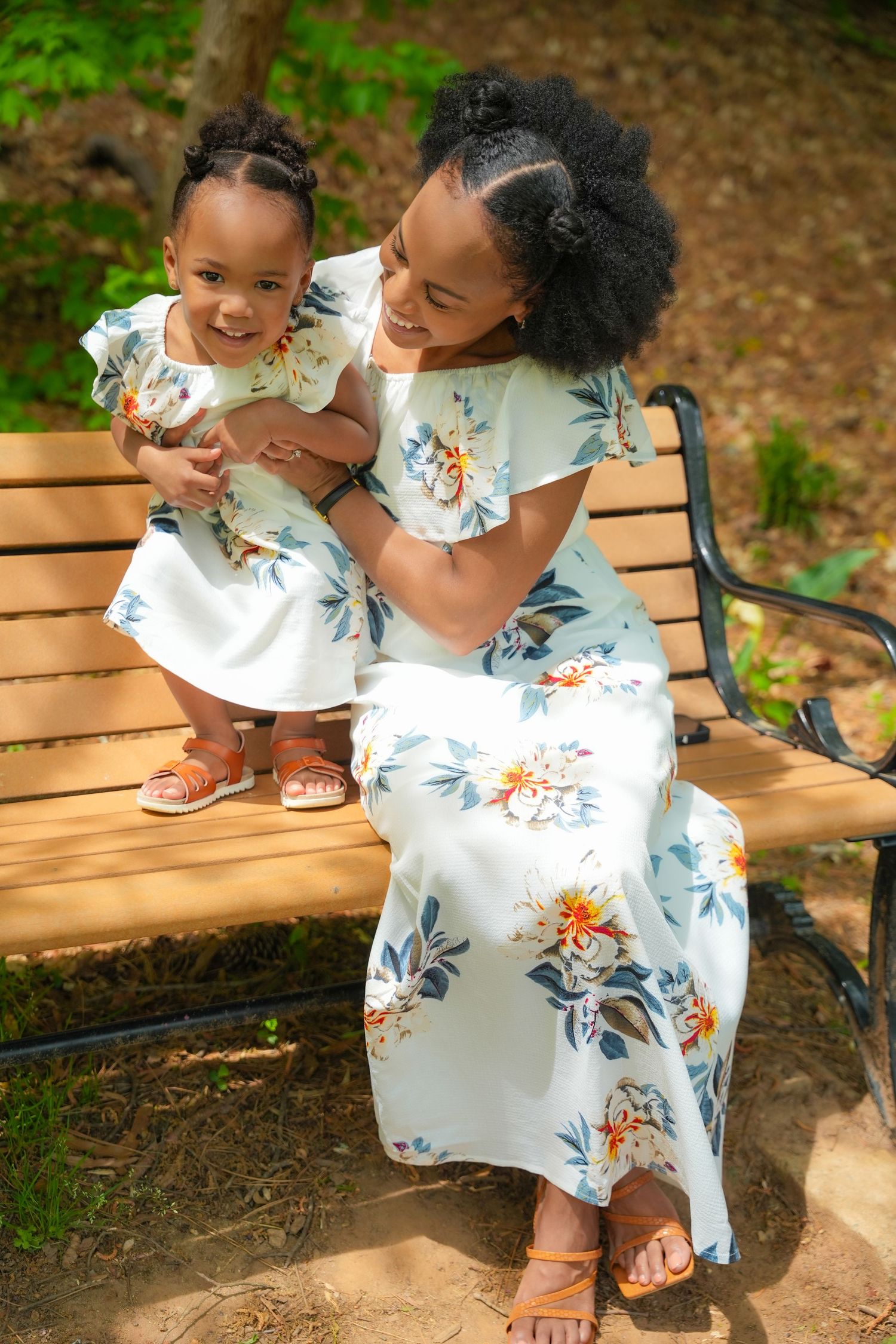 Sweet moments captured on a wooden bench in matching floral dresses.