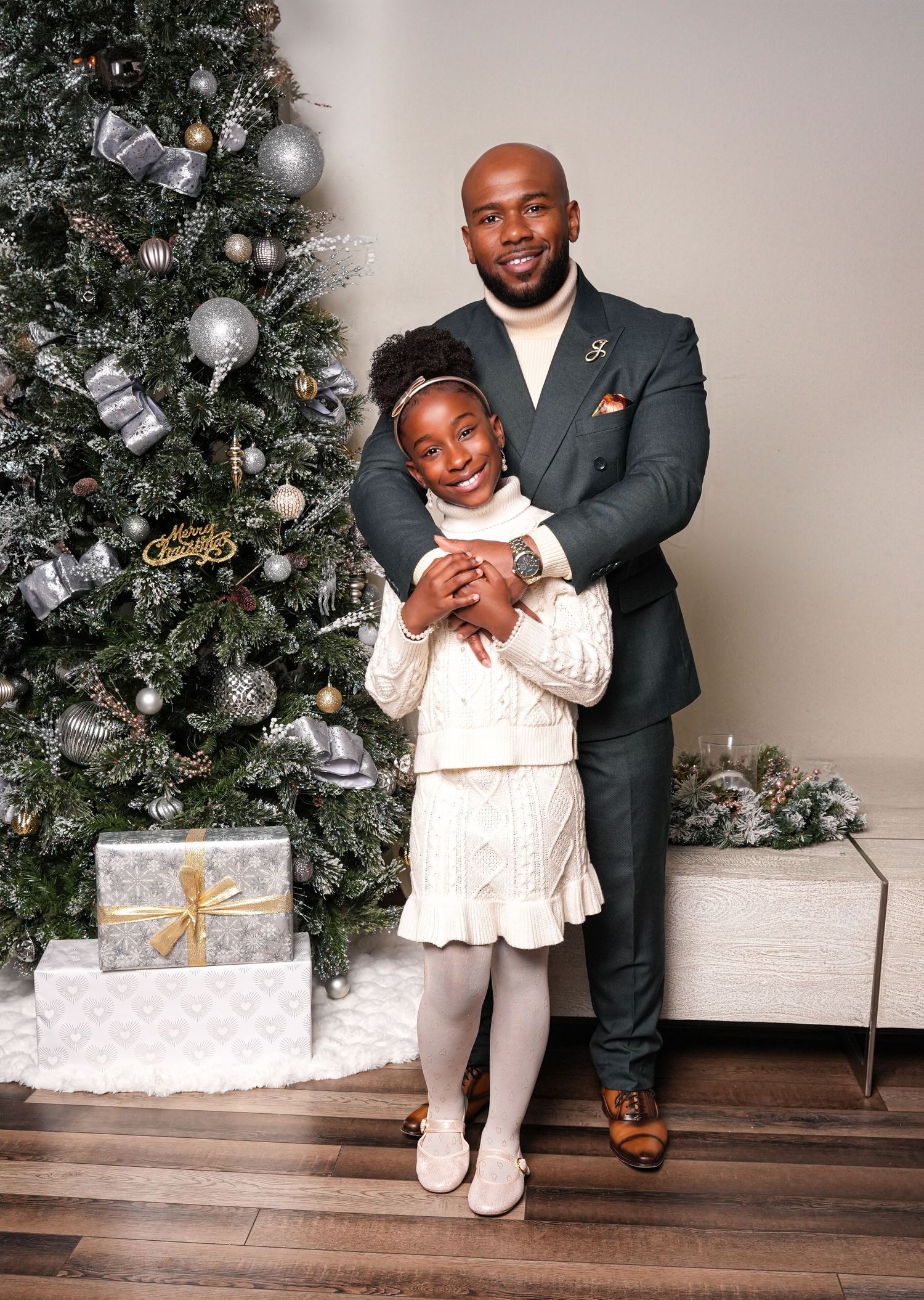Holiday portraits by a decorated Christmas tree with wrapped presents on the floor.