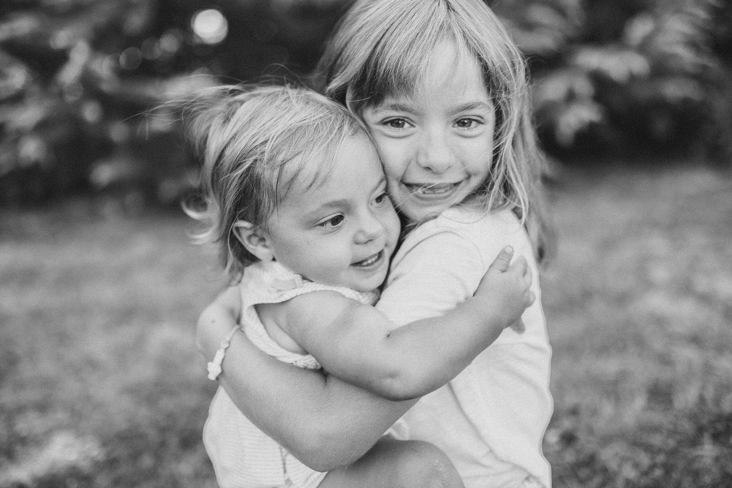 Black and white portrait of two young children hugging and smiling.