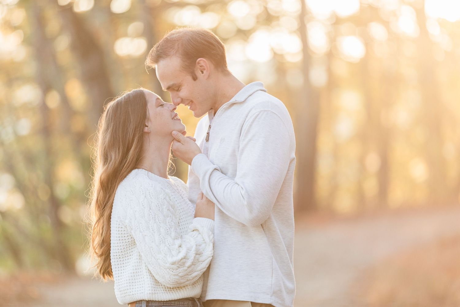 Romantic couple sharing a tender moment in a sunlit autumn forest setting.