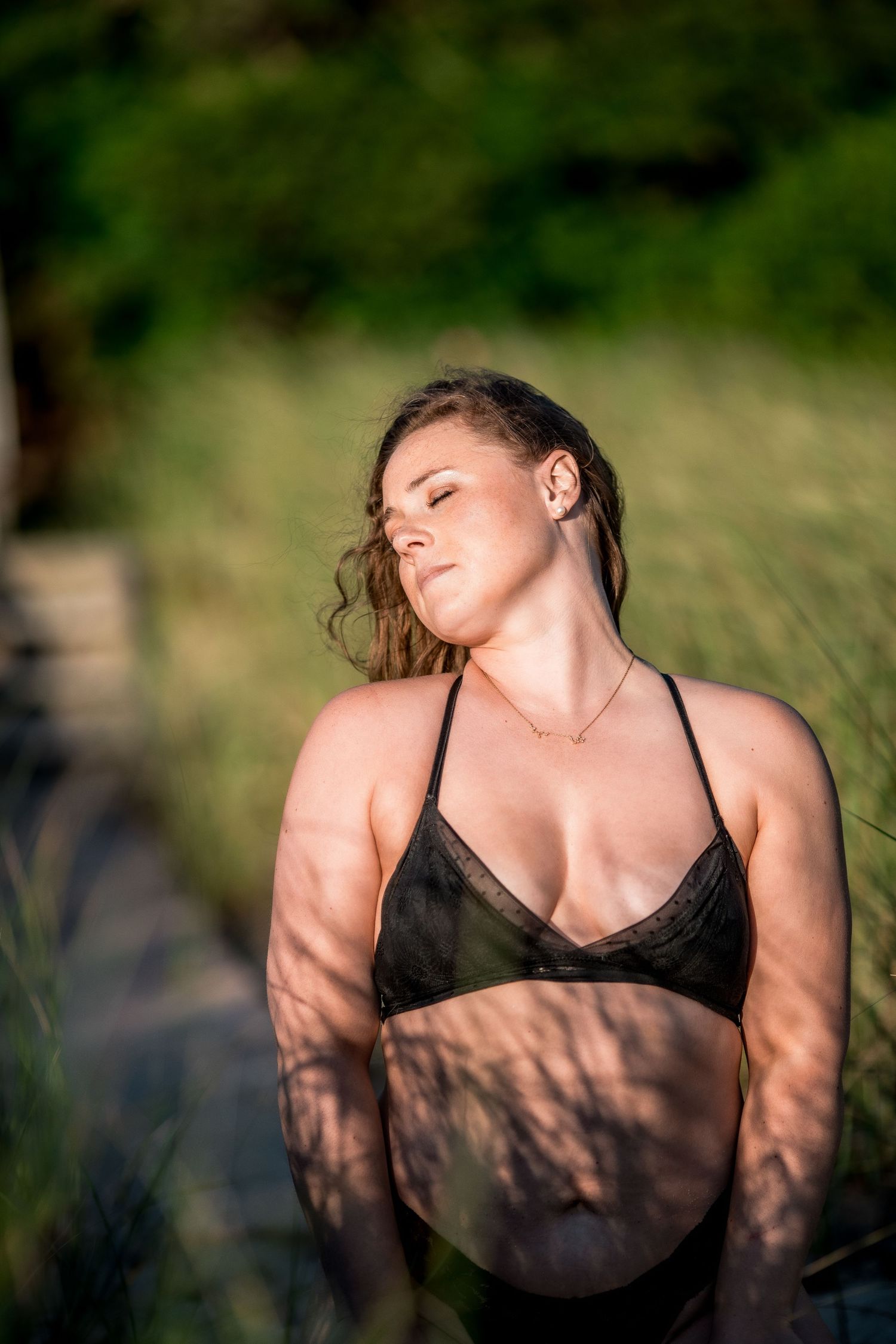 Young woman in black bikini top enjoying Cape Cod golden hour sunlight outdoors.