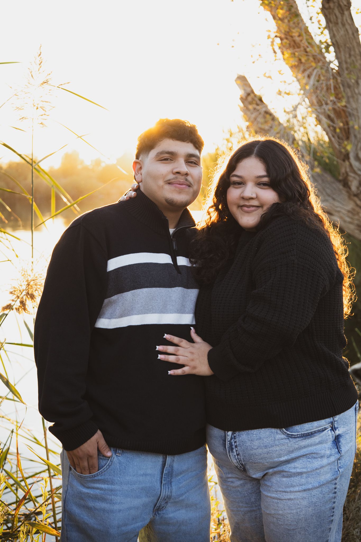 sunset image of a couple by a lake, moody but soft colors, trees, nature