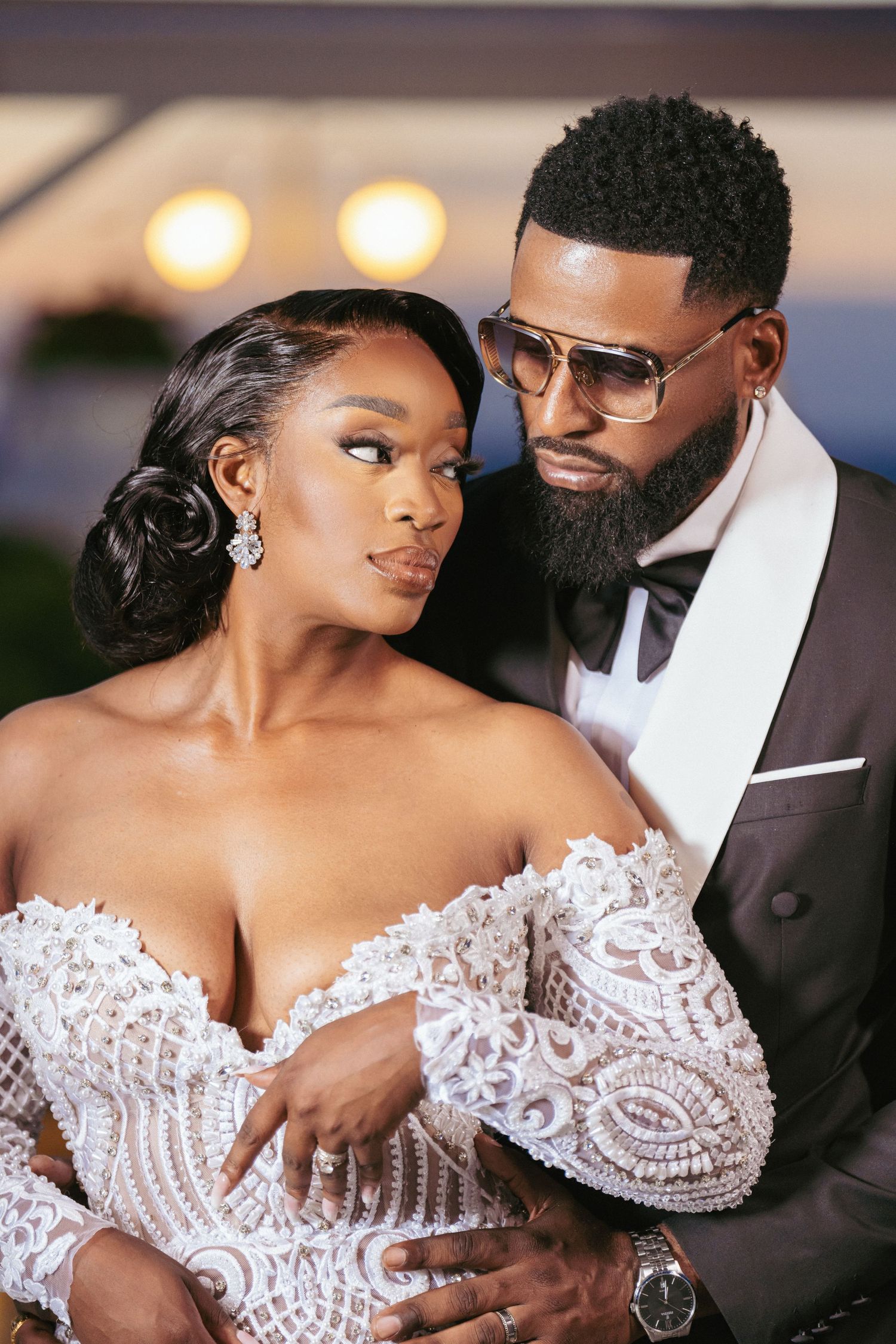 Intimate wedding portrait of couple in formal attire sharing a romantic moment at sunset.
