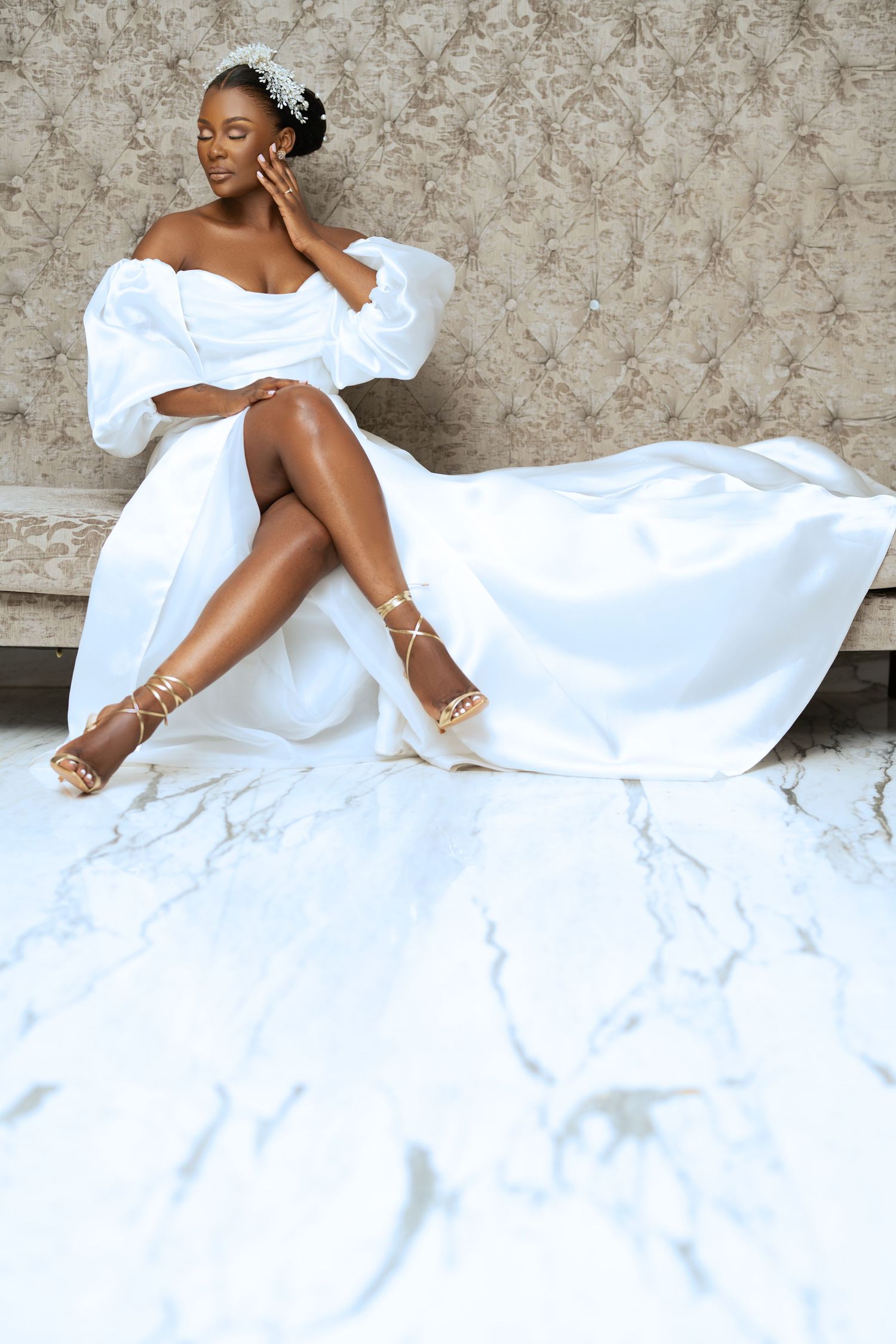 Elegant bridal portrait session on white bedding with flowing fabric.