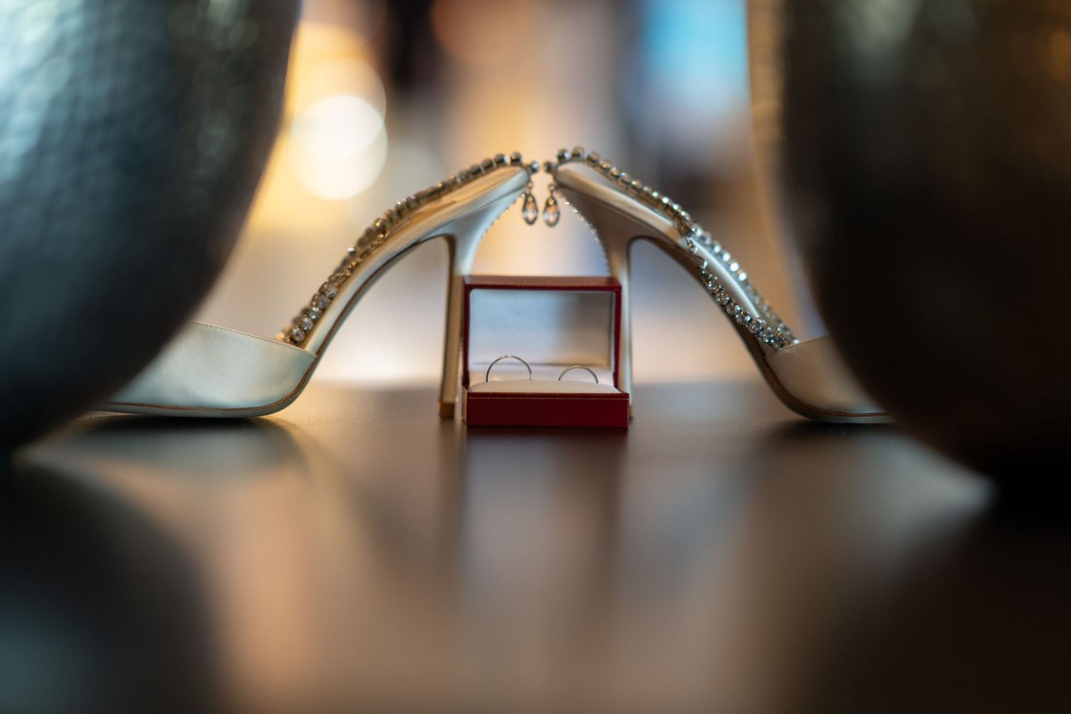 Wedding shoes artistically arranged to create a heart shape on a reflective surface.