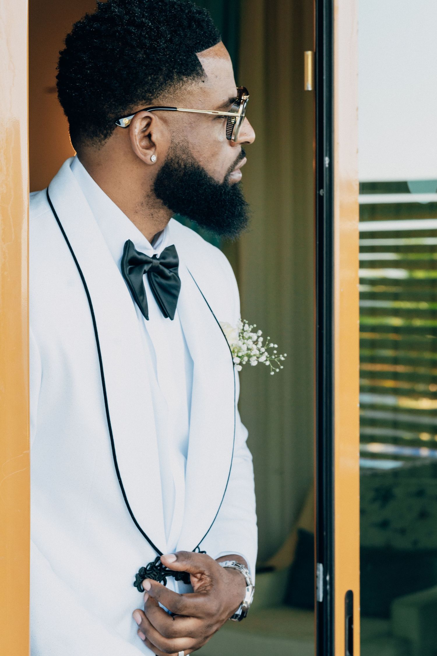Groom getting ready in crisp white suit jacket with black trim.
