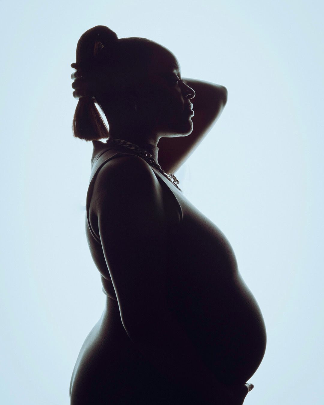 Artistic silhouette series capturing pregnancy profile against light background.