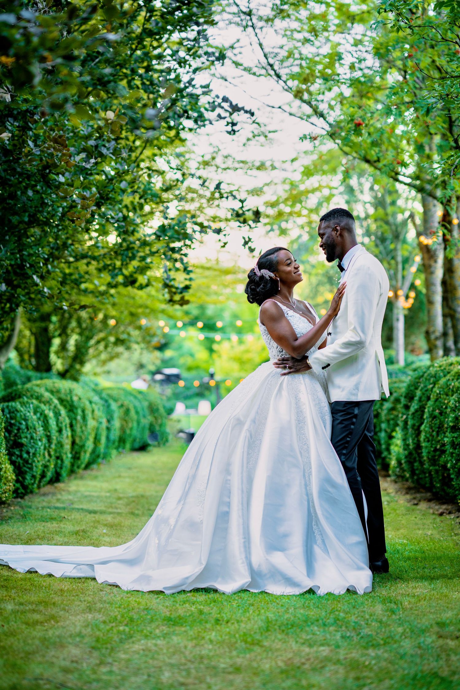 A romantic wedding photoshoot in a lush garden setting with greenery and hedges.