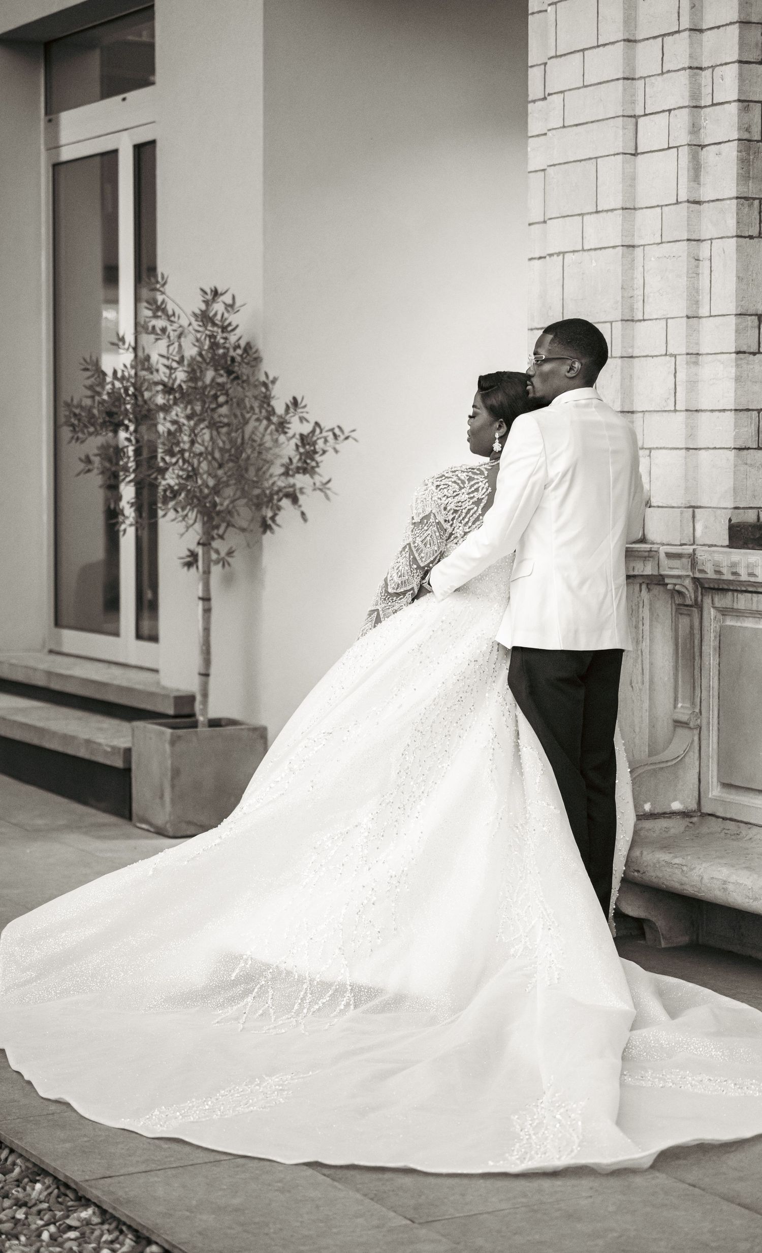 Black and white wedding portraits showing couple embracing against architectural backdrop.