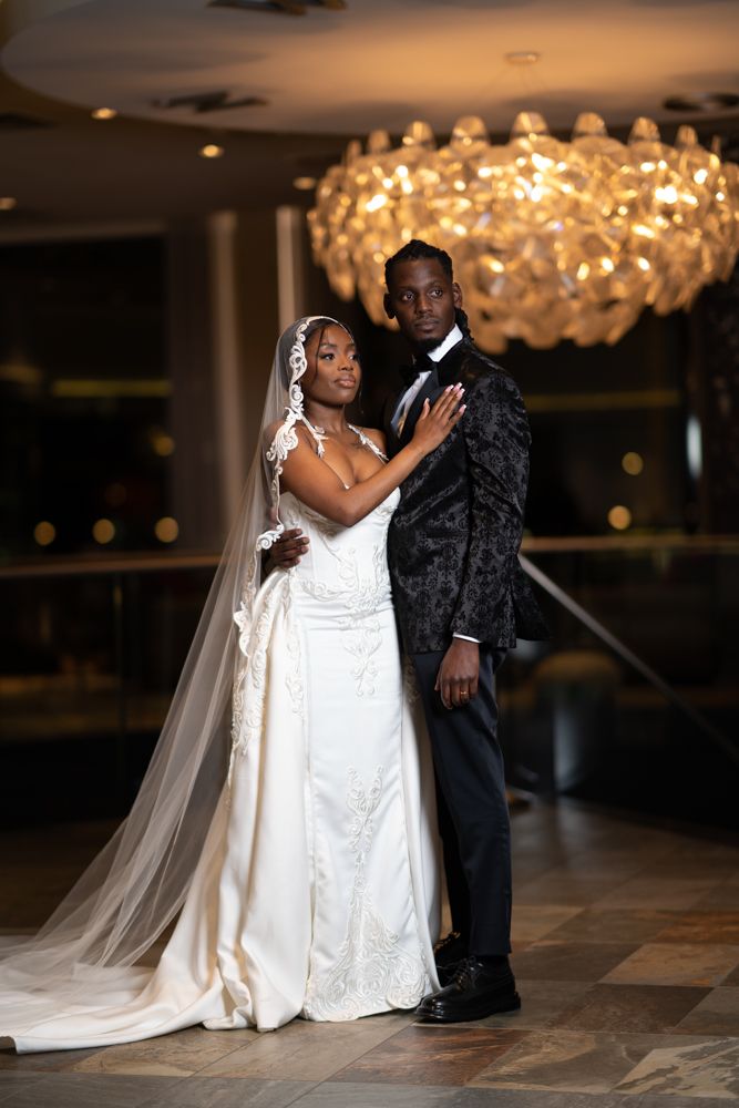 Wedding couple in formal attire dancing under crystal chandeliers.