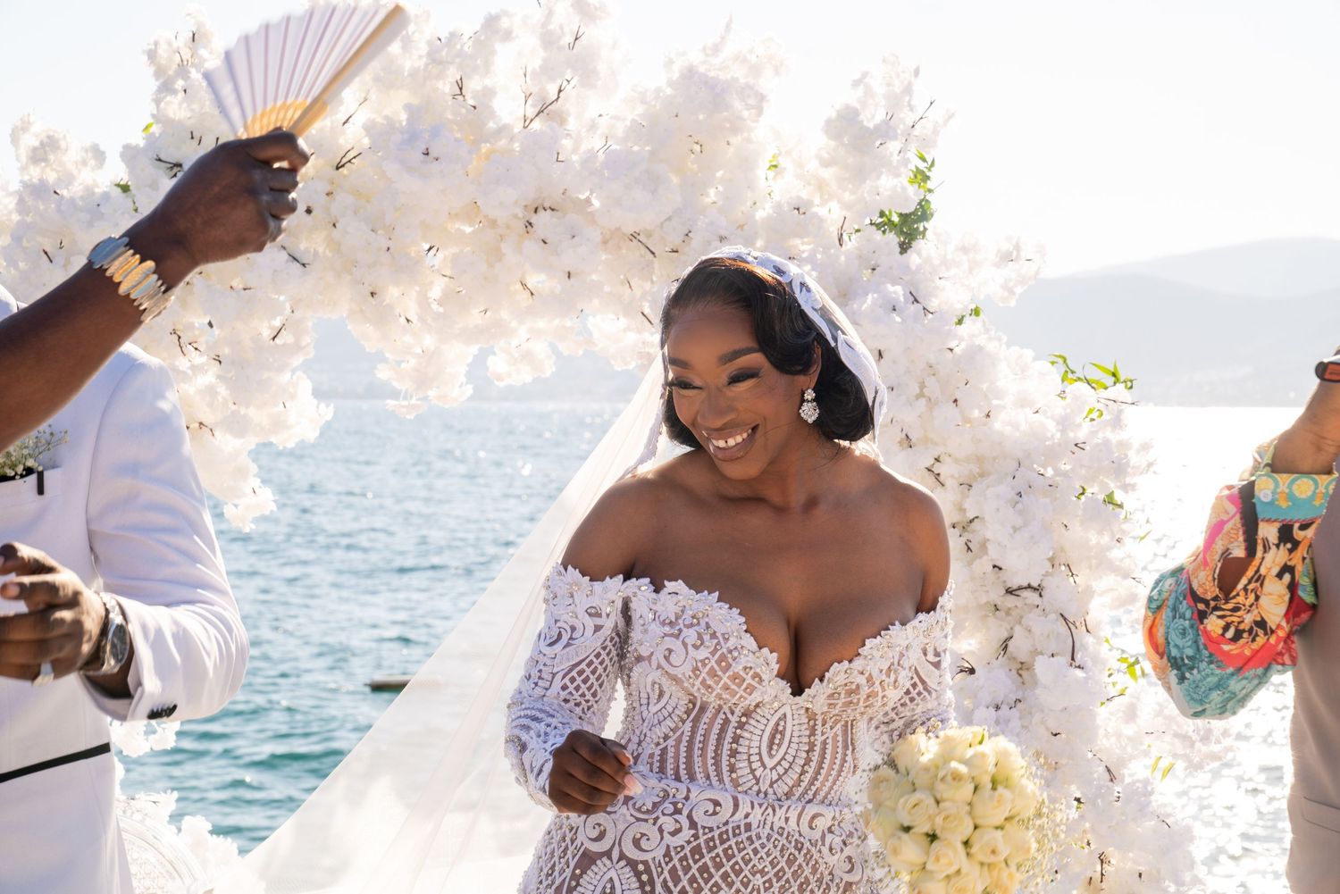 An elegant outdoor wedding ceremony setup with white floral arrangements by the ocean.