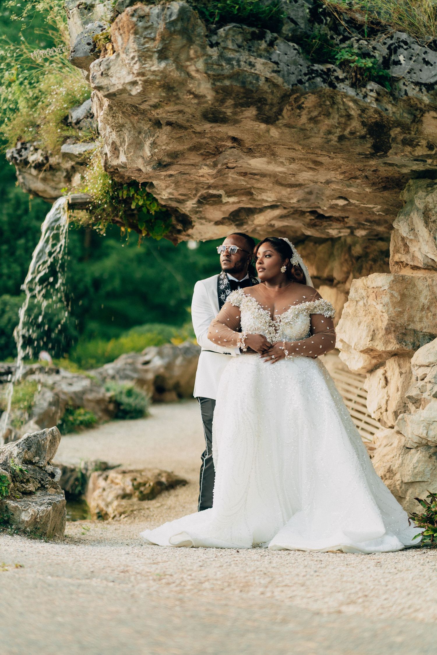 A romantic wedding photoshoot featuring a couple posing against dramatic rock formations in a natural outdoor setting.