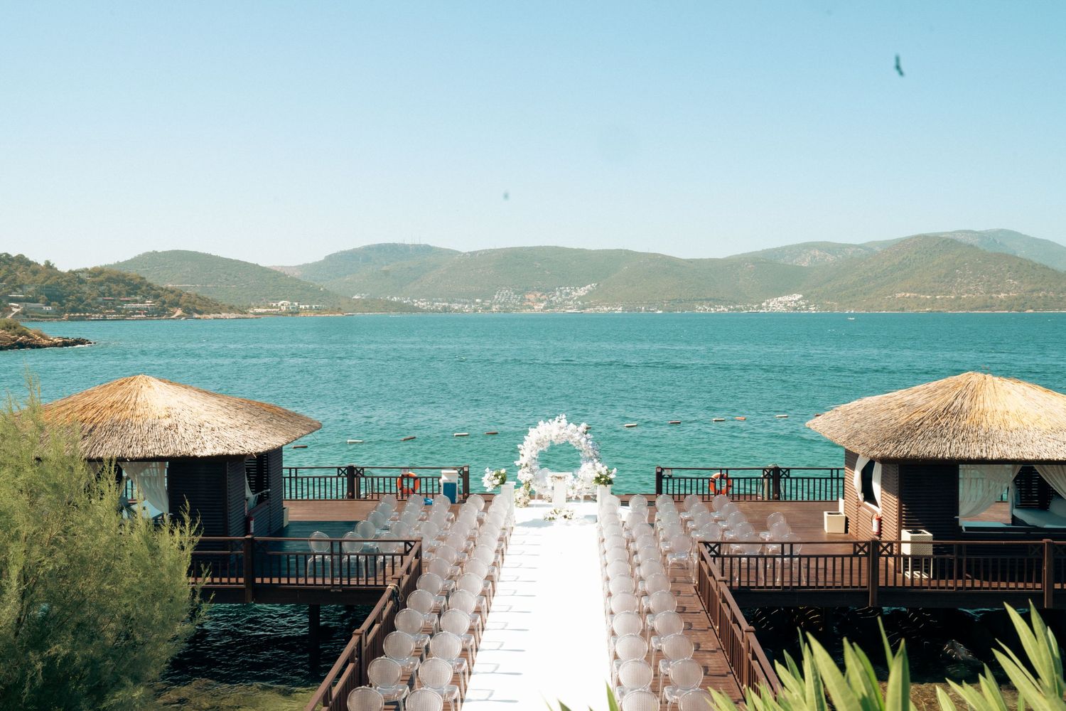 Scenic waterfront venue with wooden deck overlooking blue waters and mountains.
