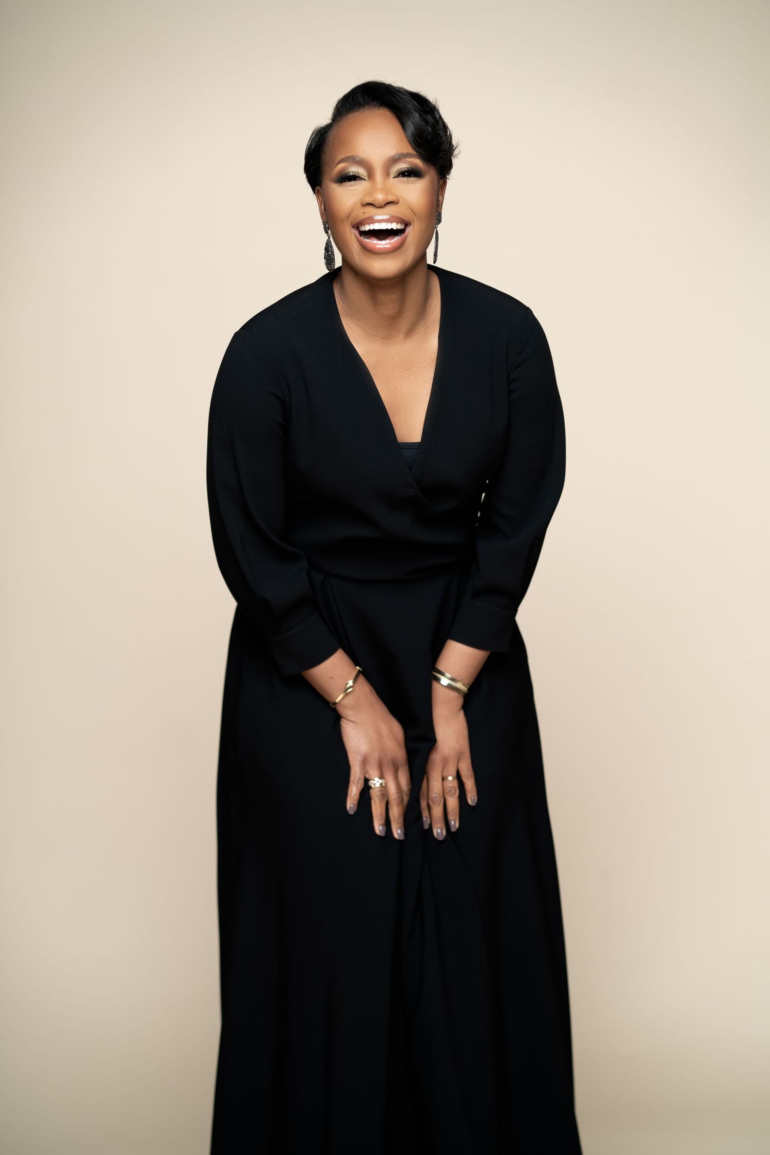 Professional studio portraits showing joyful expressions in elegant black attire against neutral backdrop.