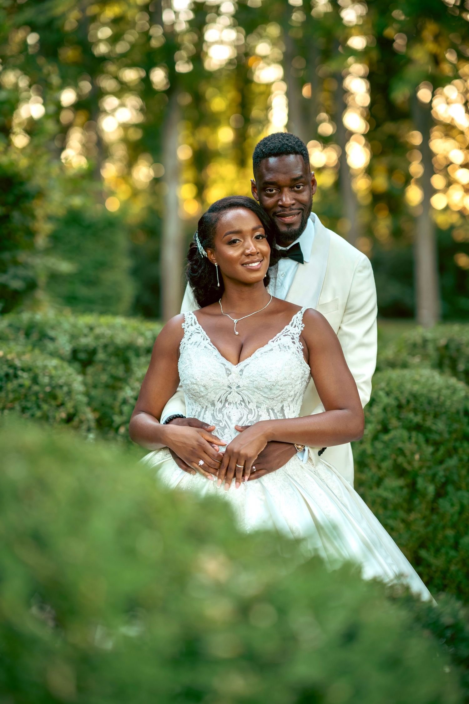 Romantic wedding portraits of a couple in white attire against a sunset-lit garden backdrop.